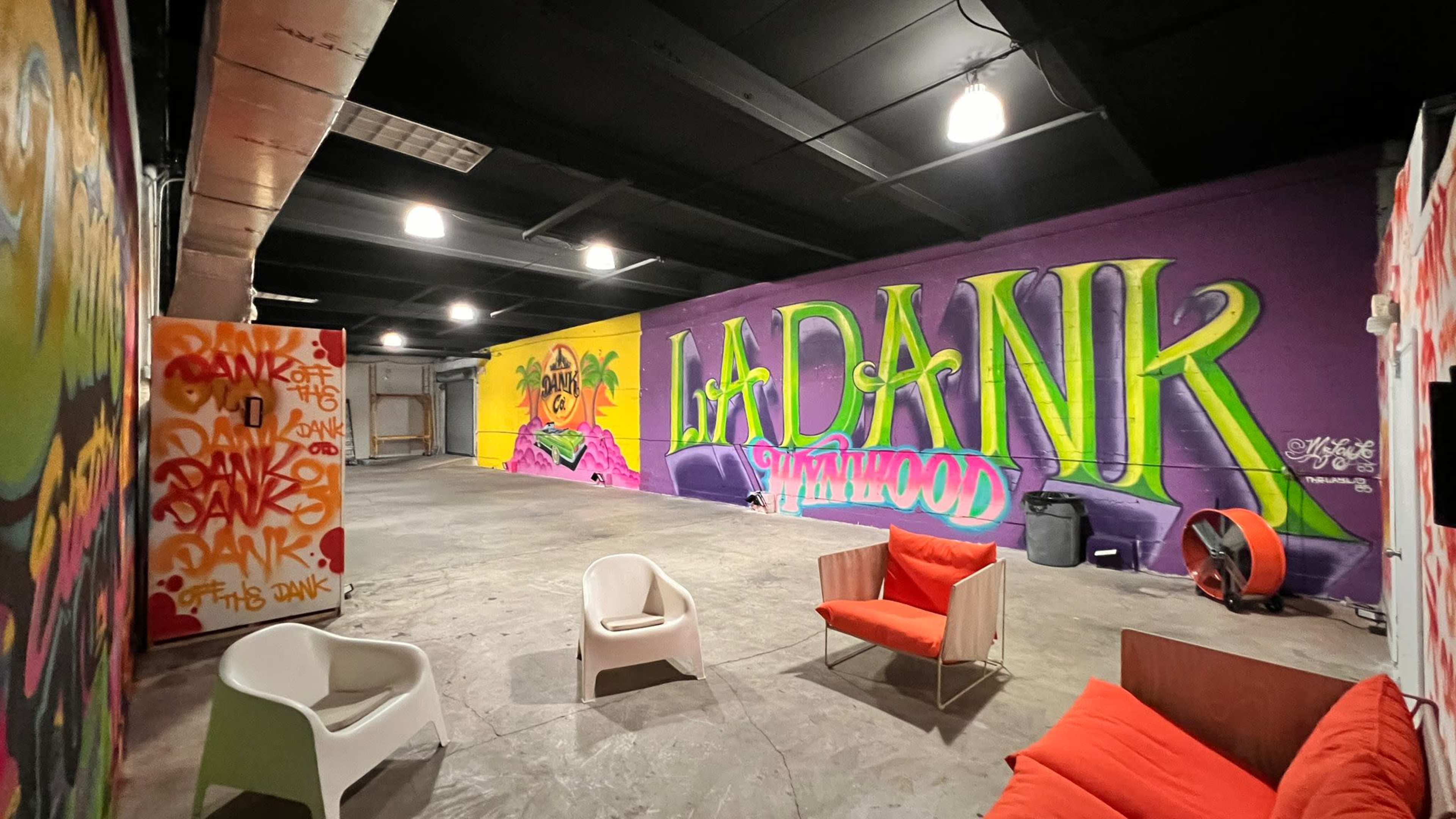 The image shows an industrial room with colorful graffiti on the walls and modern furniture arranged in a casual setting.