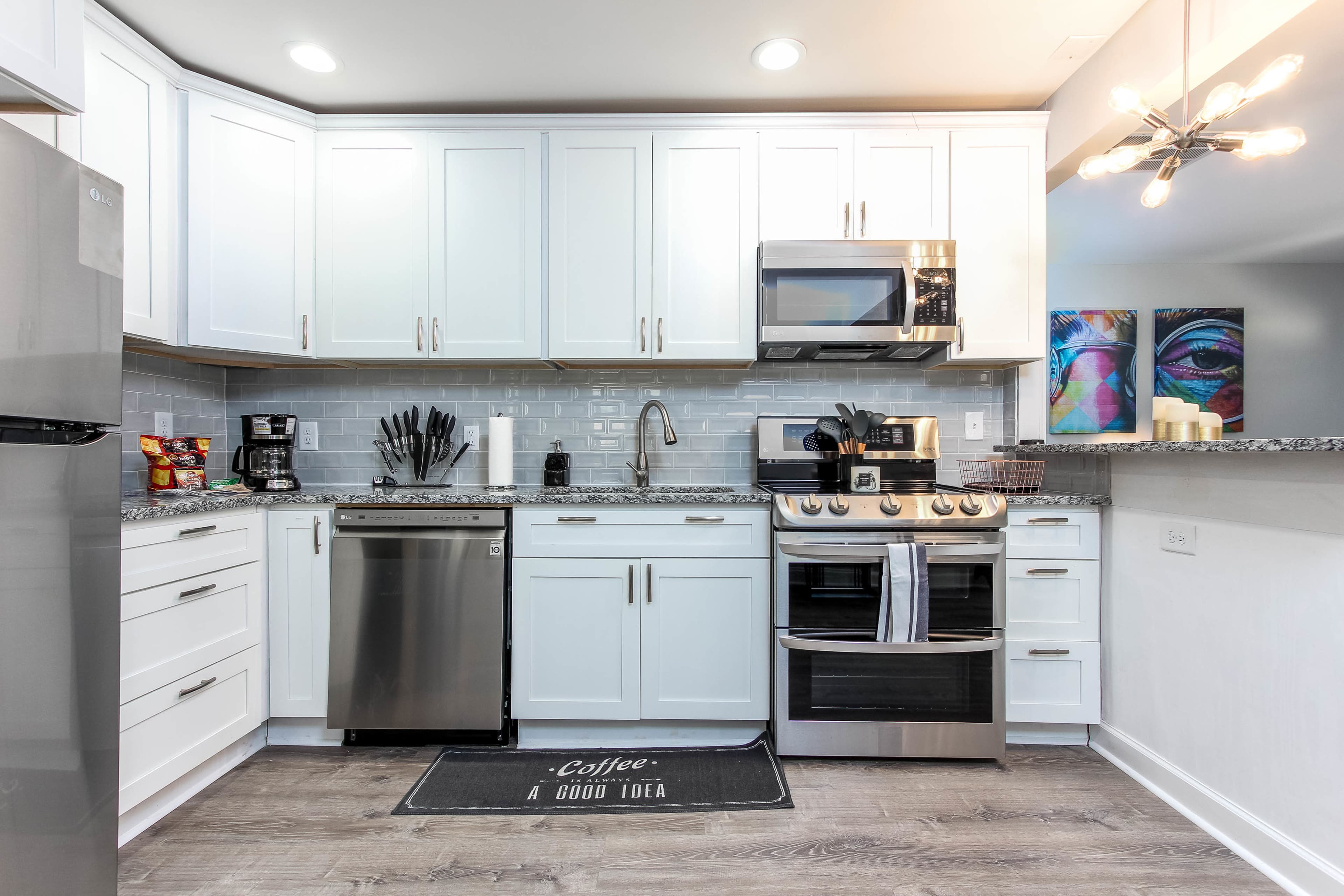 A modern kitchen features white cabinets, stainless steel appliances, and a gray tile backsplash.