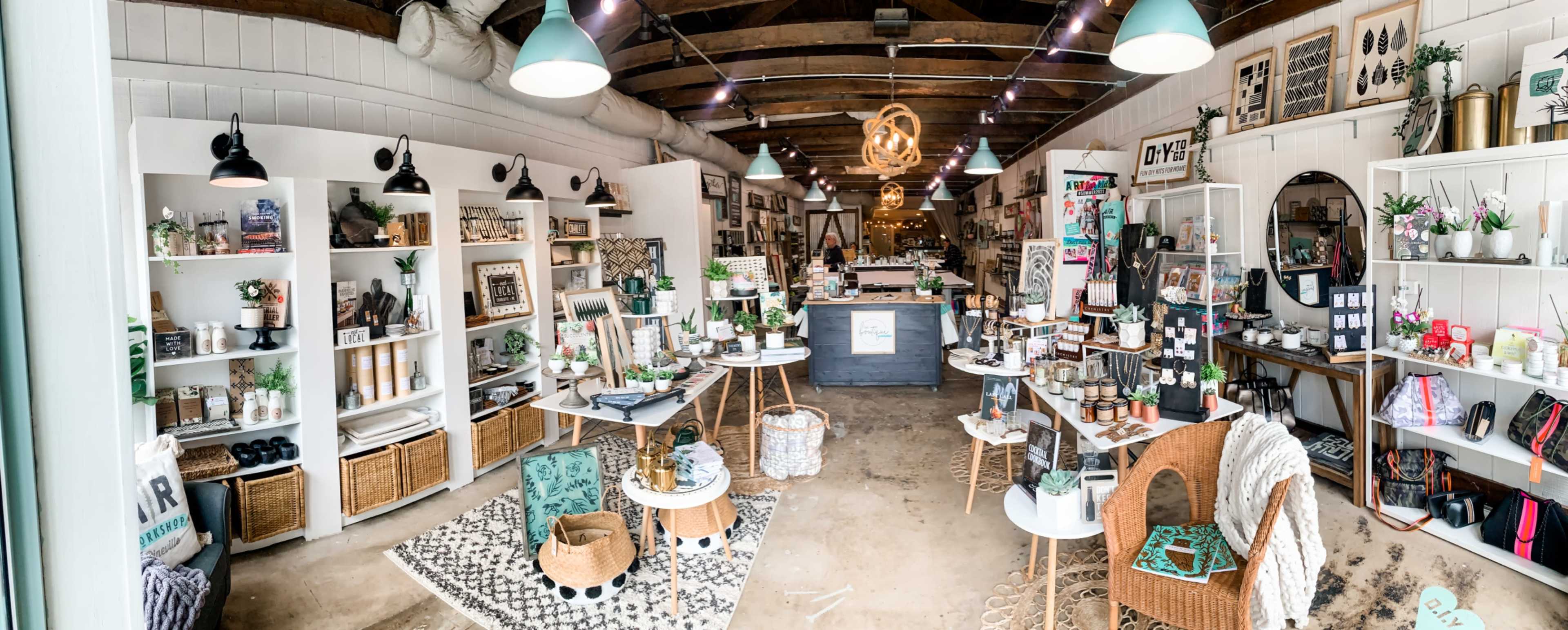 A well-organized interior of a retail store featuring various home decor items, plants, and furniture arranged on display shelves and tables.