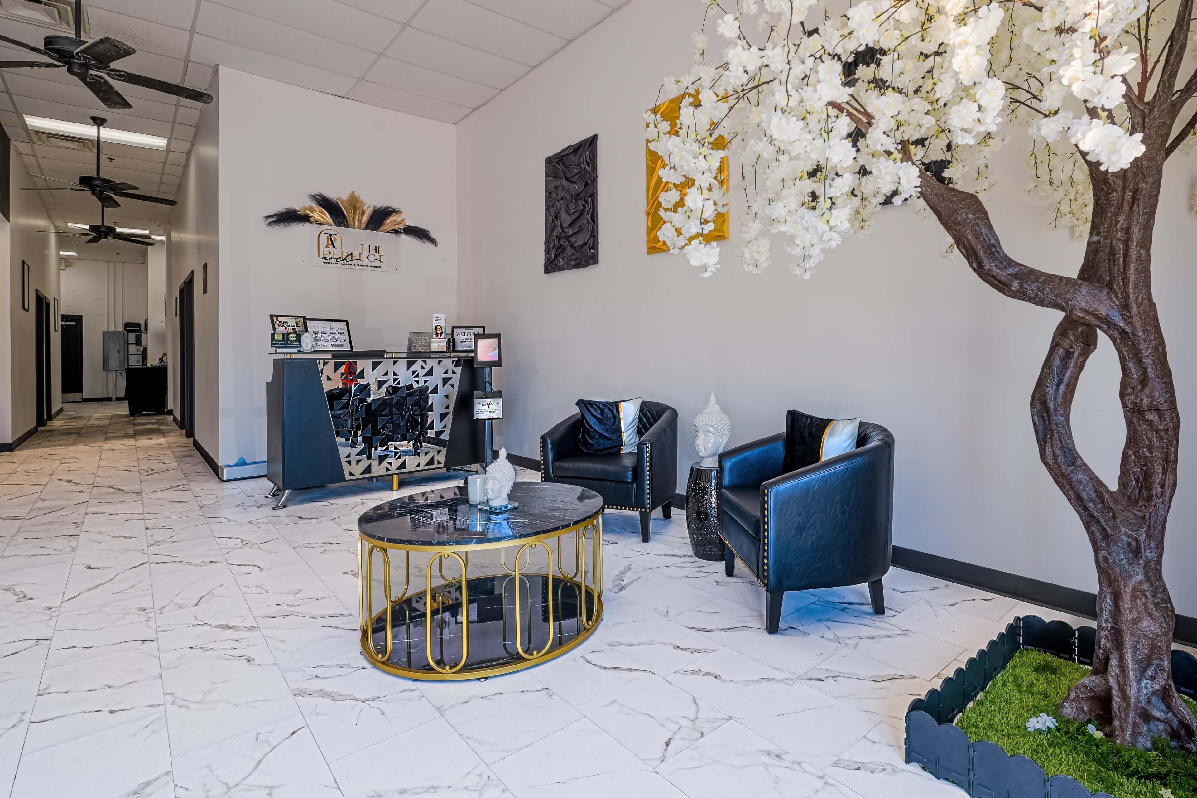 A neatly arranged reception area with black chairs, a decorative coffee table, and a faux flowering tree.