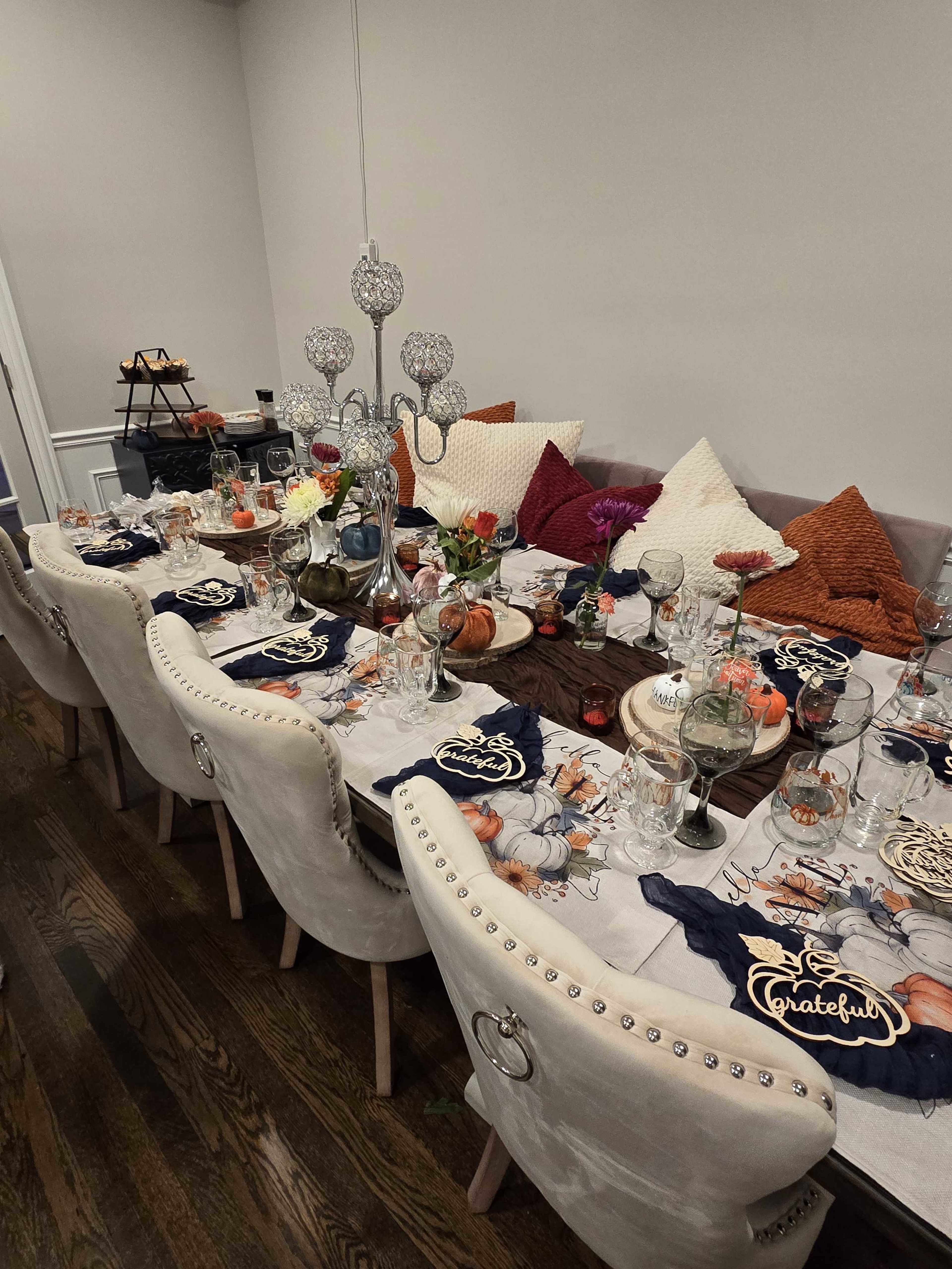 A long dining table is set with decorative tableware, colorful napkins, and centerpieces, ready for a gathering.