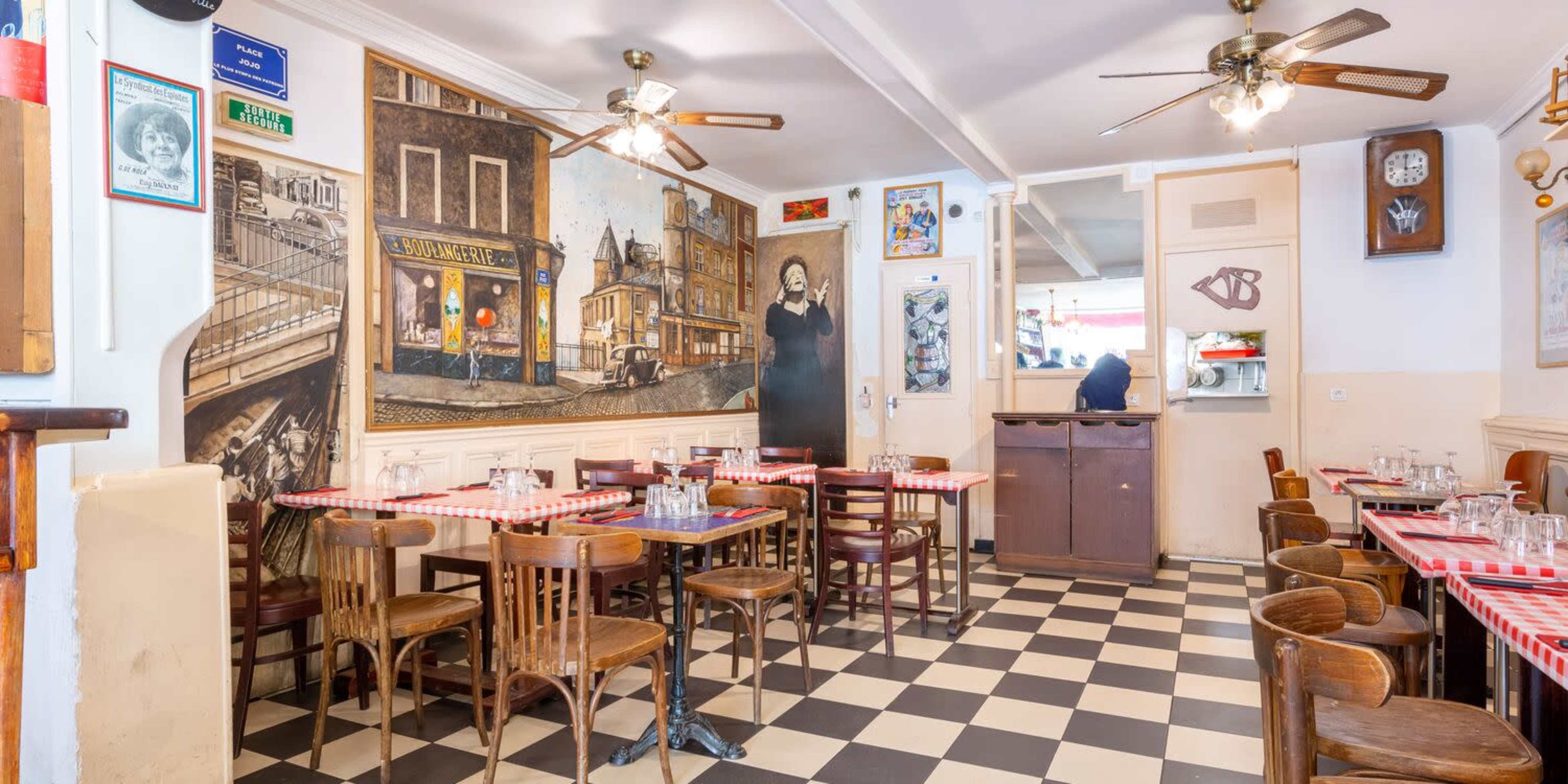The image shows a cafe interior featuring checkered flooring, wooden tables and chairs, and vintage wall decorations.