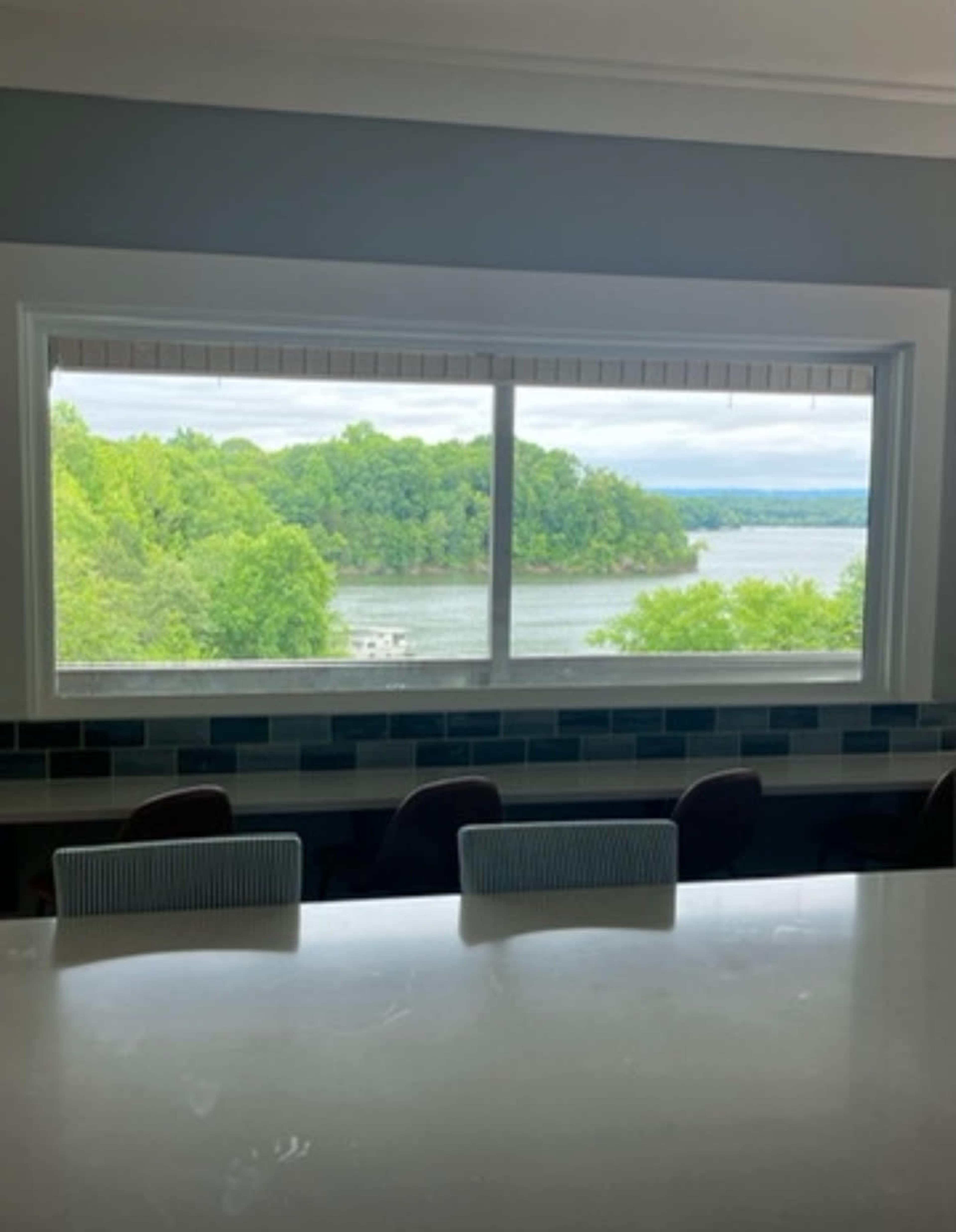 A large window frames a view of a lush green landscape and a lake.