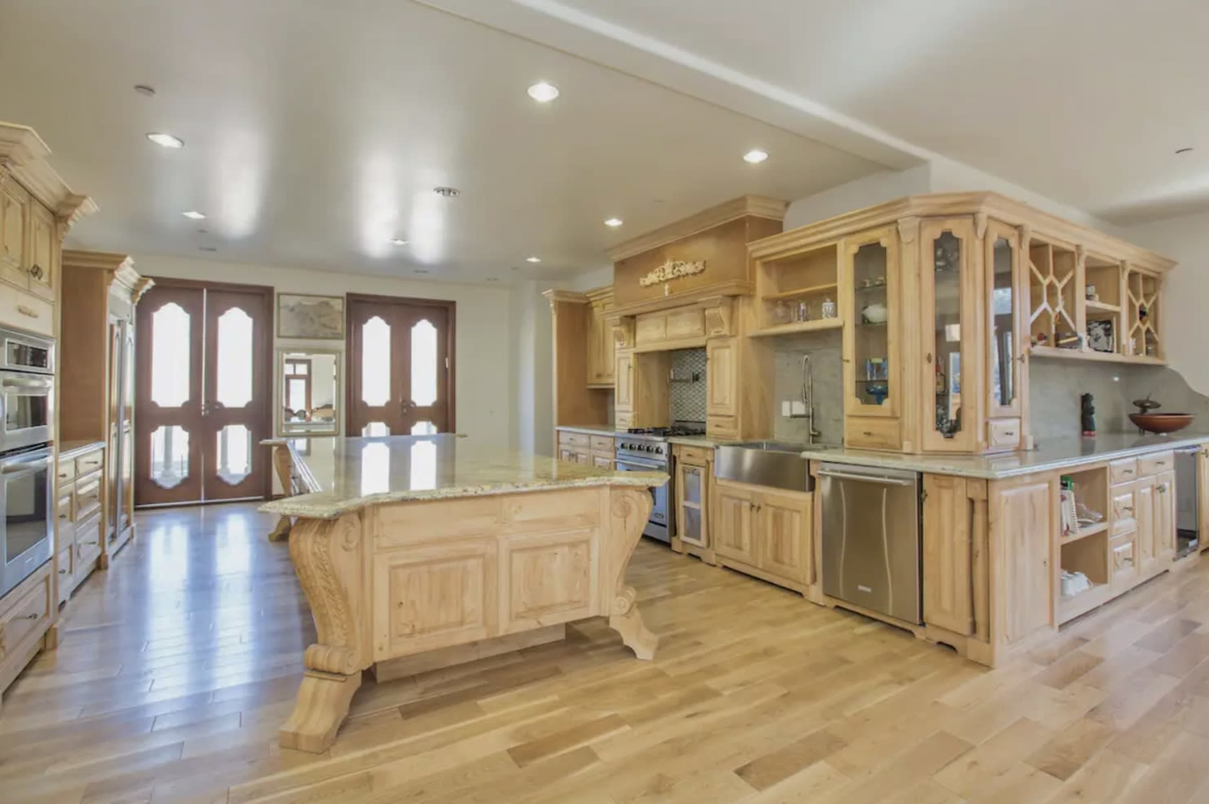 The image shows a spacious kitchen featuring wooden cabinetry, a central island, and modern appliances.