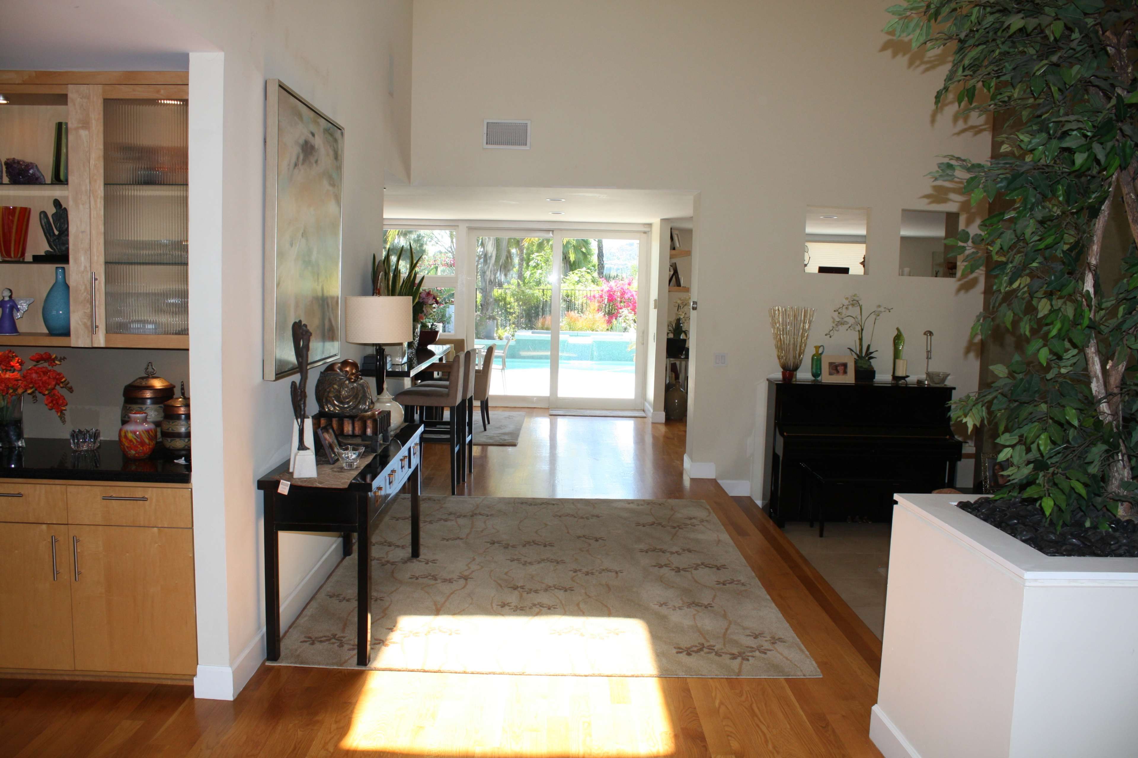 A spacious, bright interior of a home with a view of a pool area through large sliding glass doors.