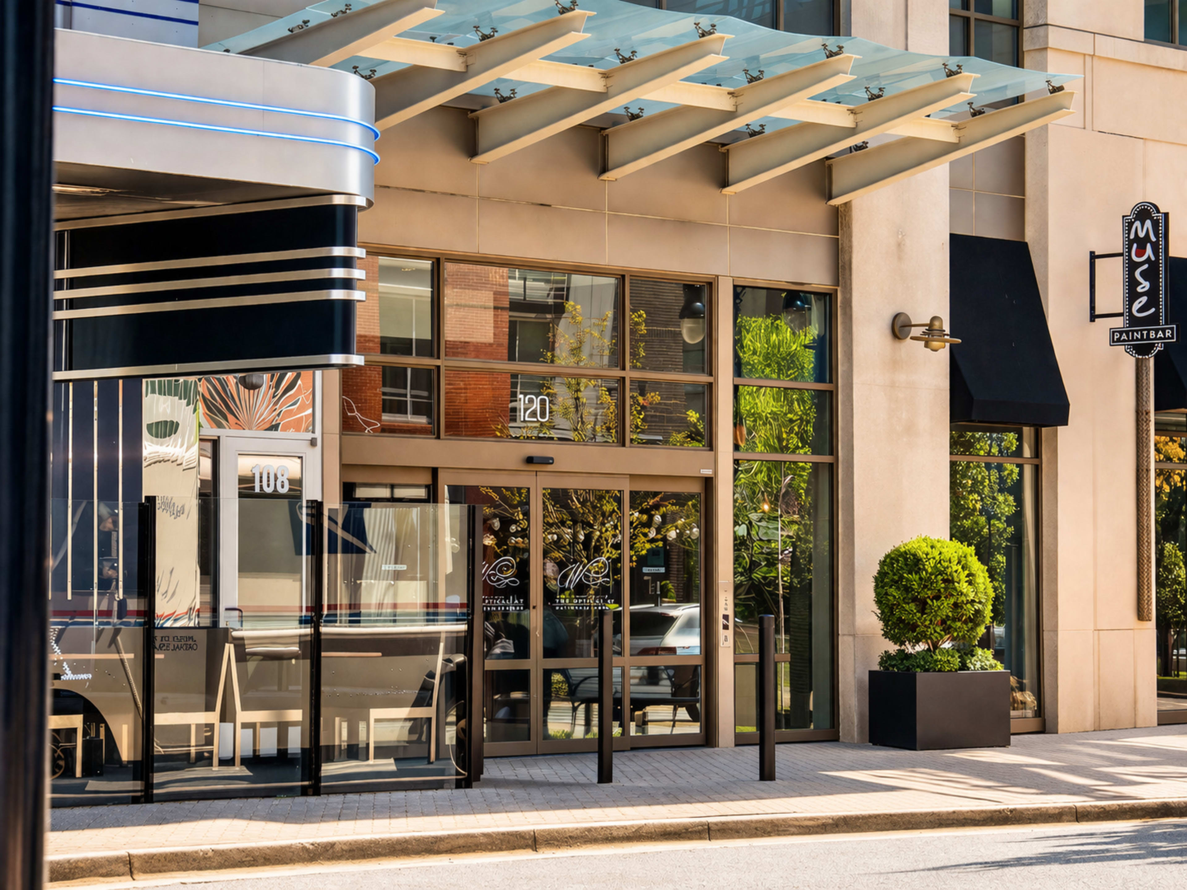 The image shows the entrance of a modern commercial building with large glass doors and a flat canopy, featuring the numbers "120" prominently displayed.