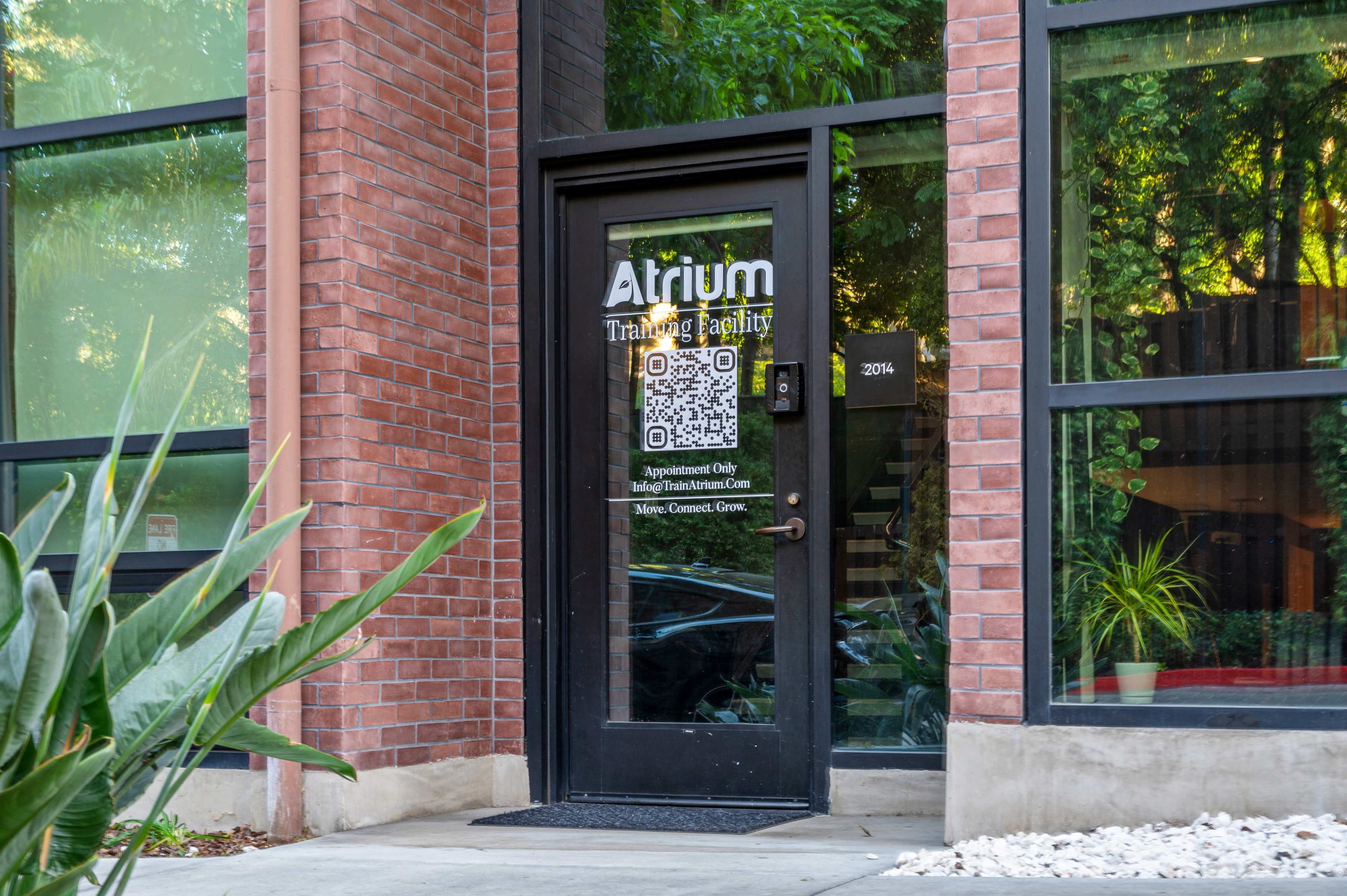 The entrance of the Atrium Training Facility, featuring a door with a QR code and information on appointments.