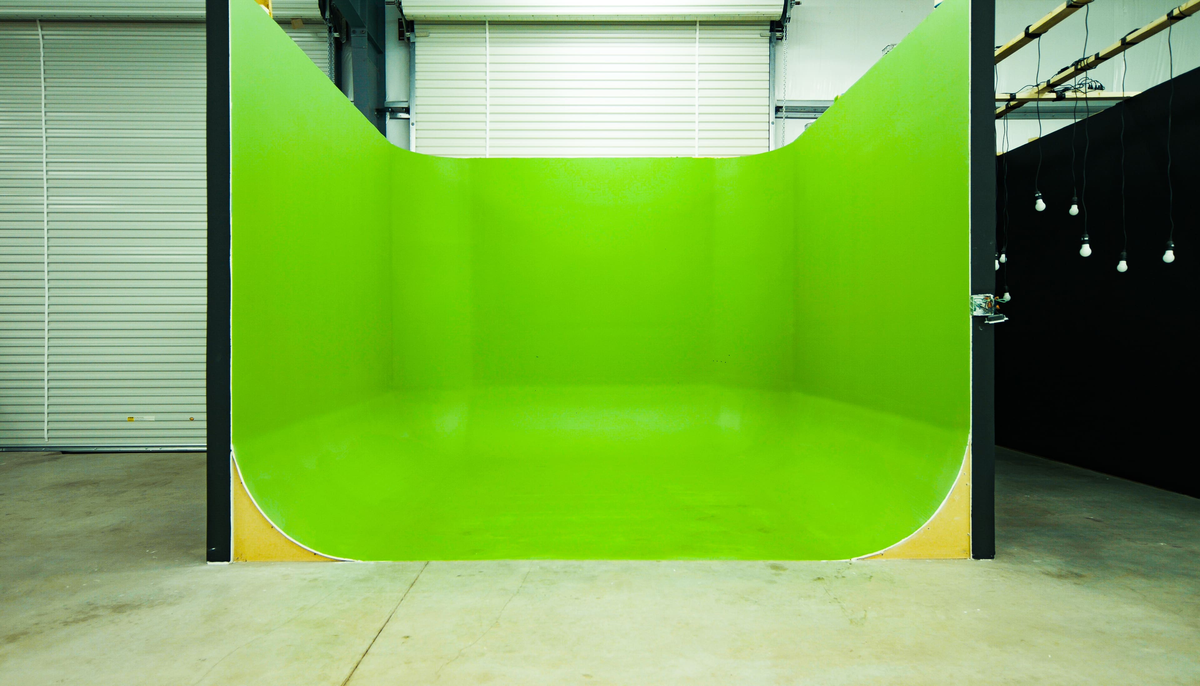 A brightly colored green curved room with a seamless, glossy surface and minimalistic lighting.