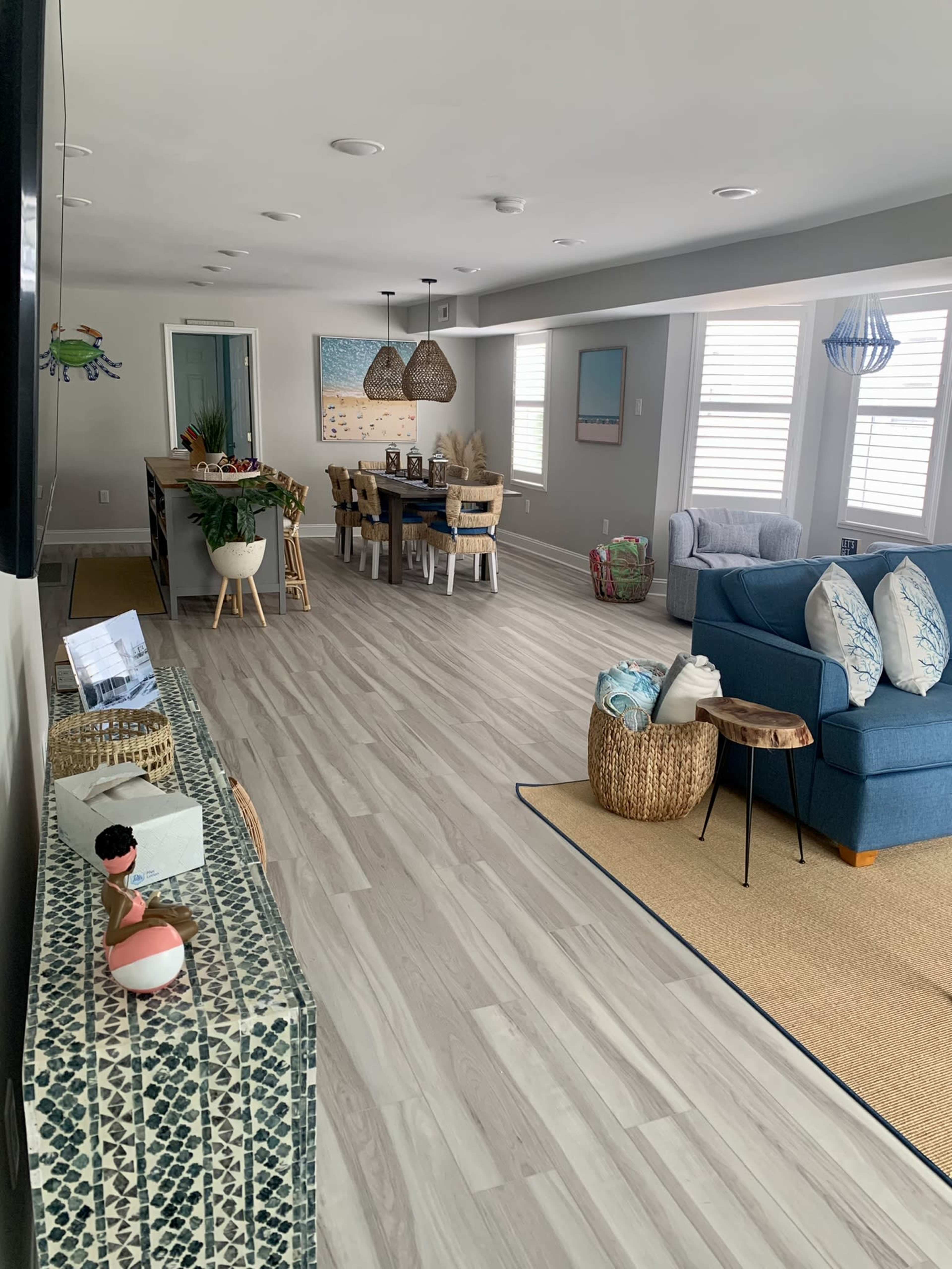 A modern, open-concept living area with a seating arrangement, a dining table, and decorative elements in a light-colored space.