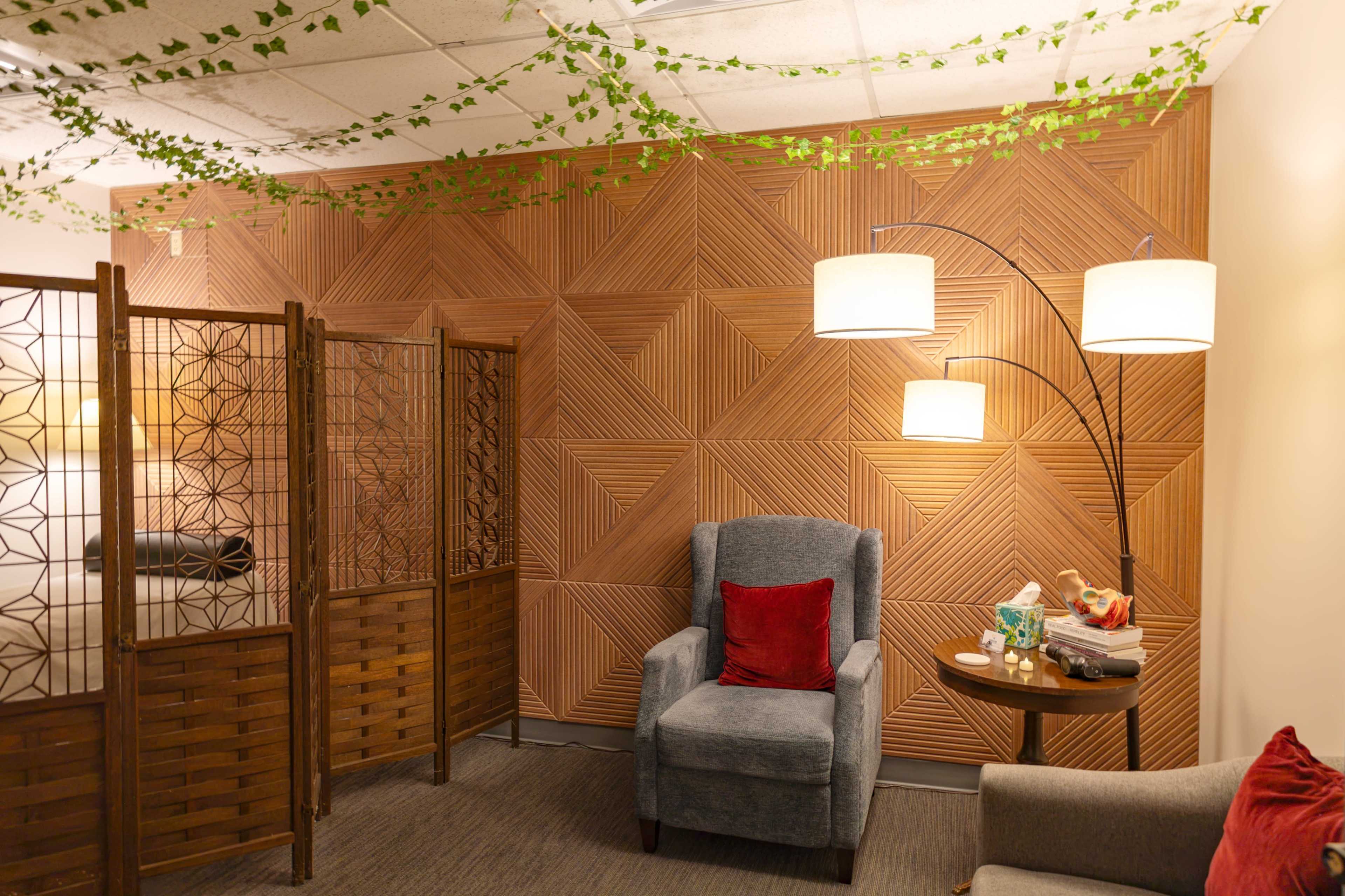 The image depicts a cozy room with wooden paneling, an armchair, a side table, and decorative room dividers.