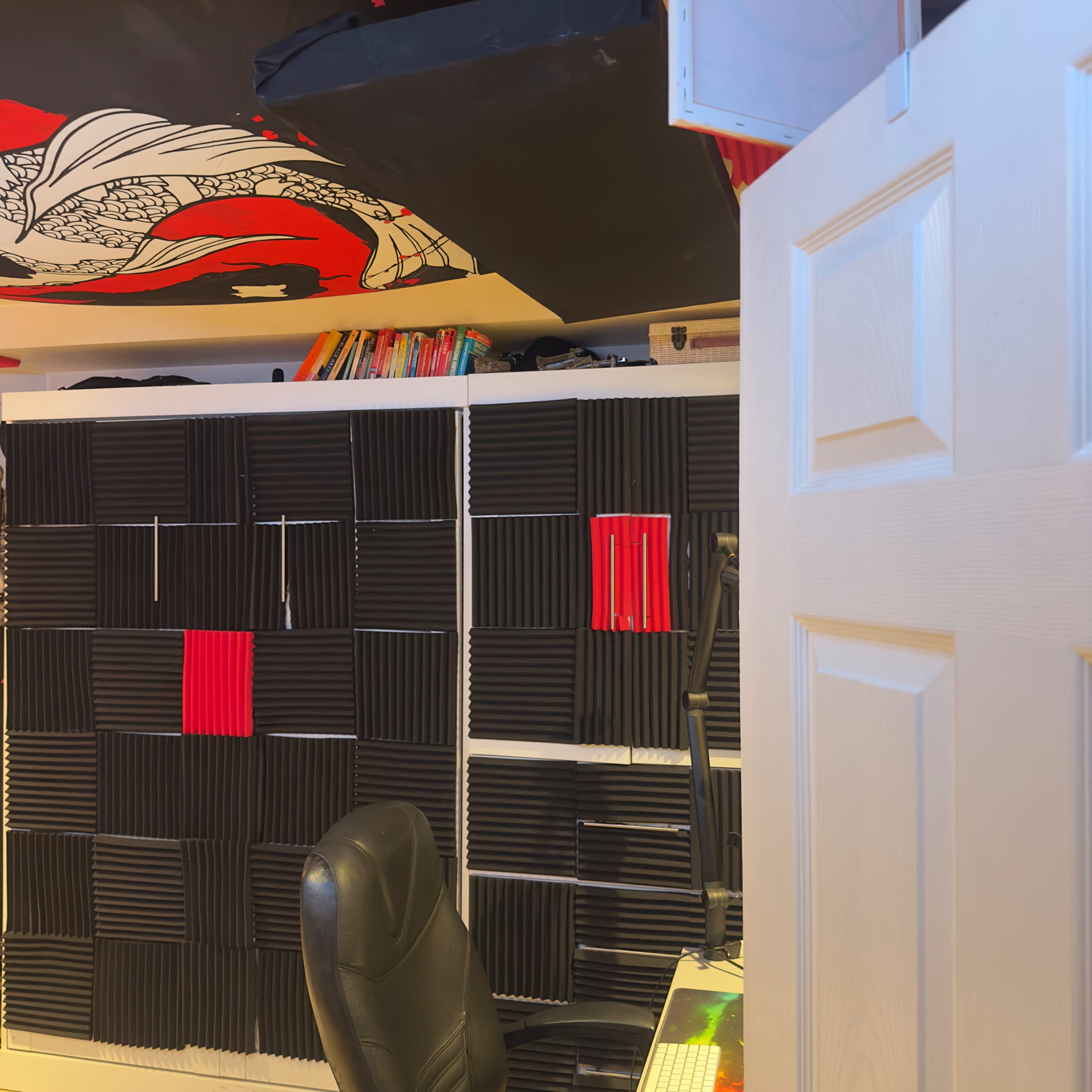 The image shows a room with a ceiling mural, soundproofing panels on the walls, and a black office chair in front of a desk.