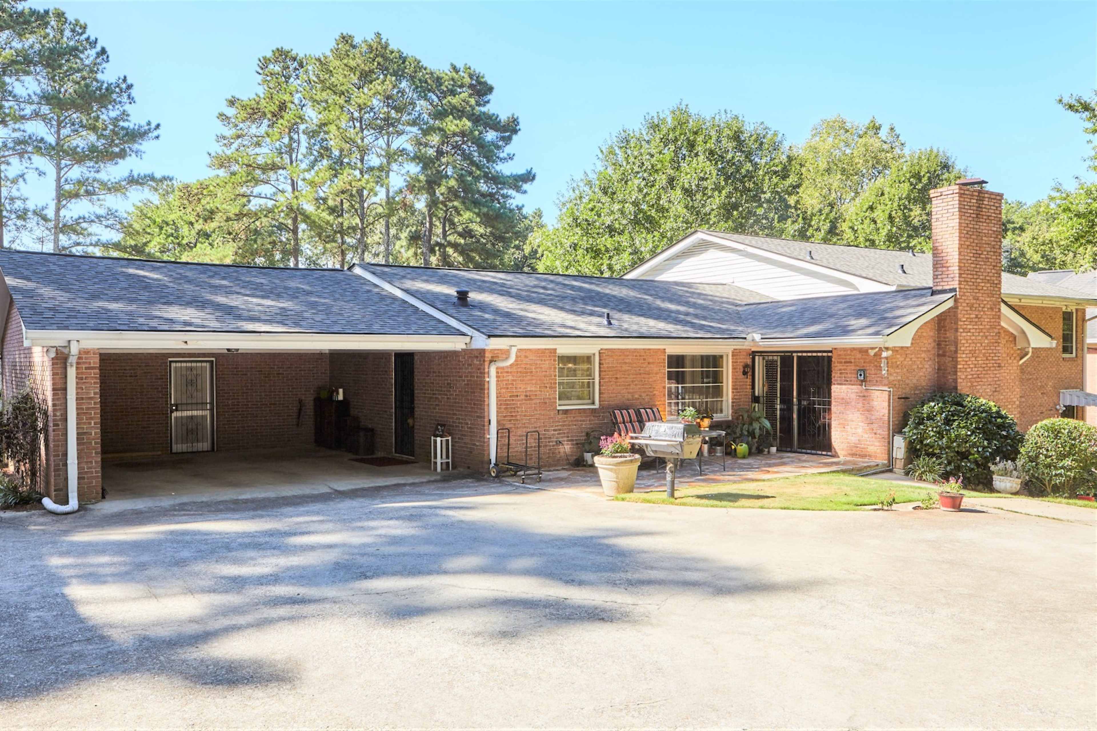 A single-story brick house with a carport and a landscaped front yard.