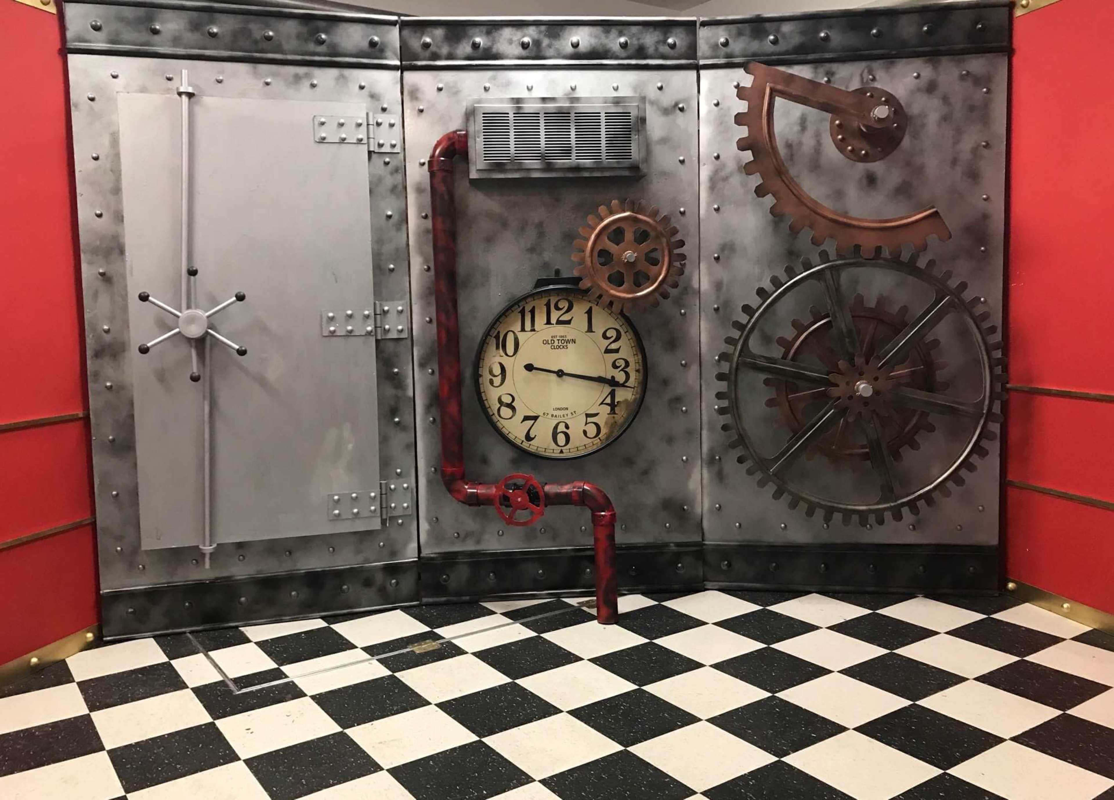 An industrial-themed room with a large clock and various mechanical gears mounted on a metallic wall.