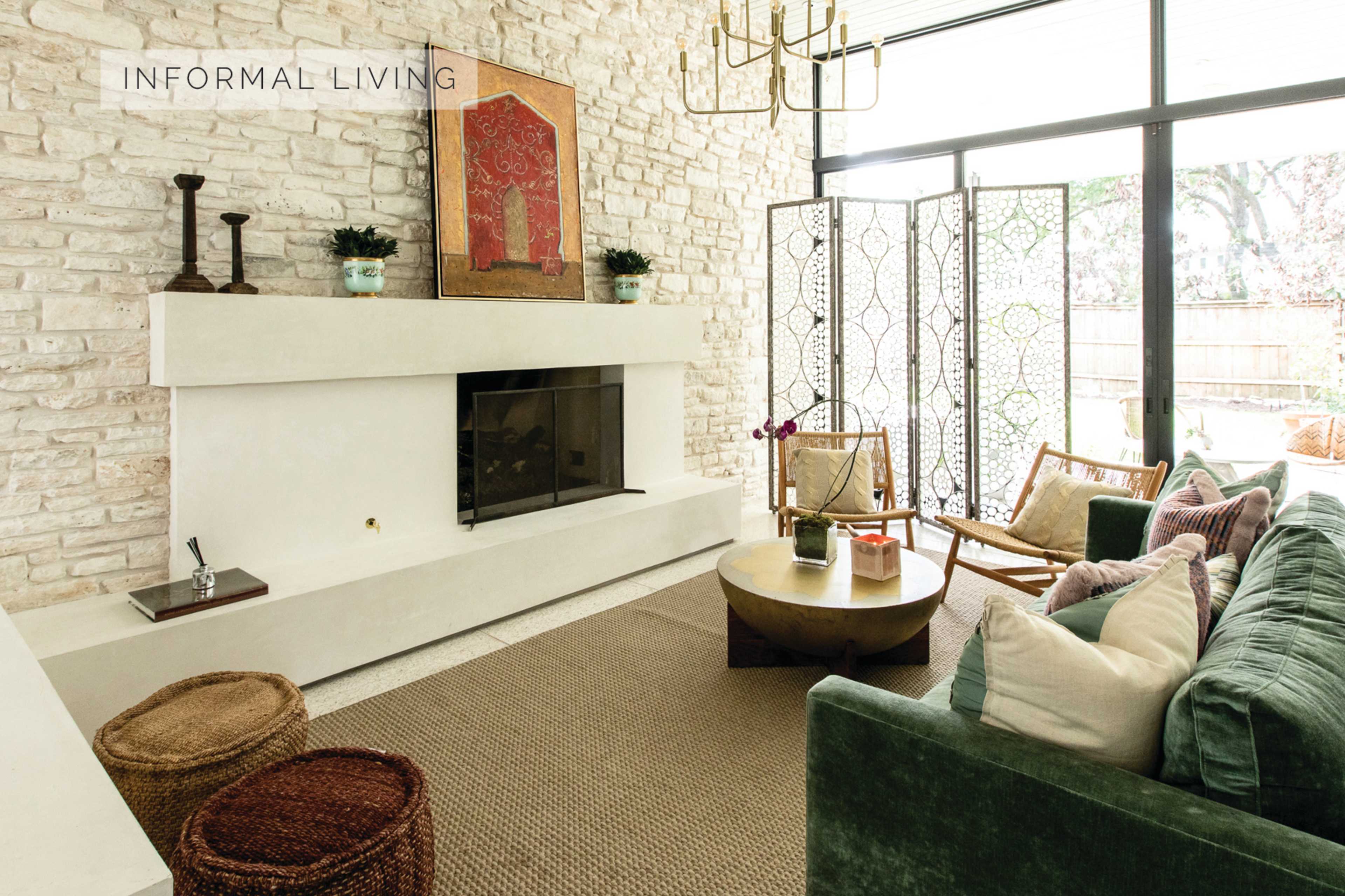 A bright living room with a stone wall, a fireplace, and a mix of modern and vintage furniture, including a round coffee table and woven baskets.