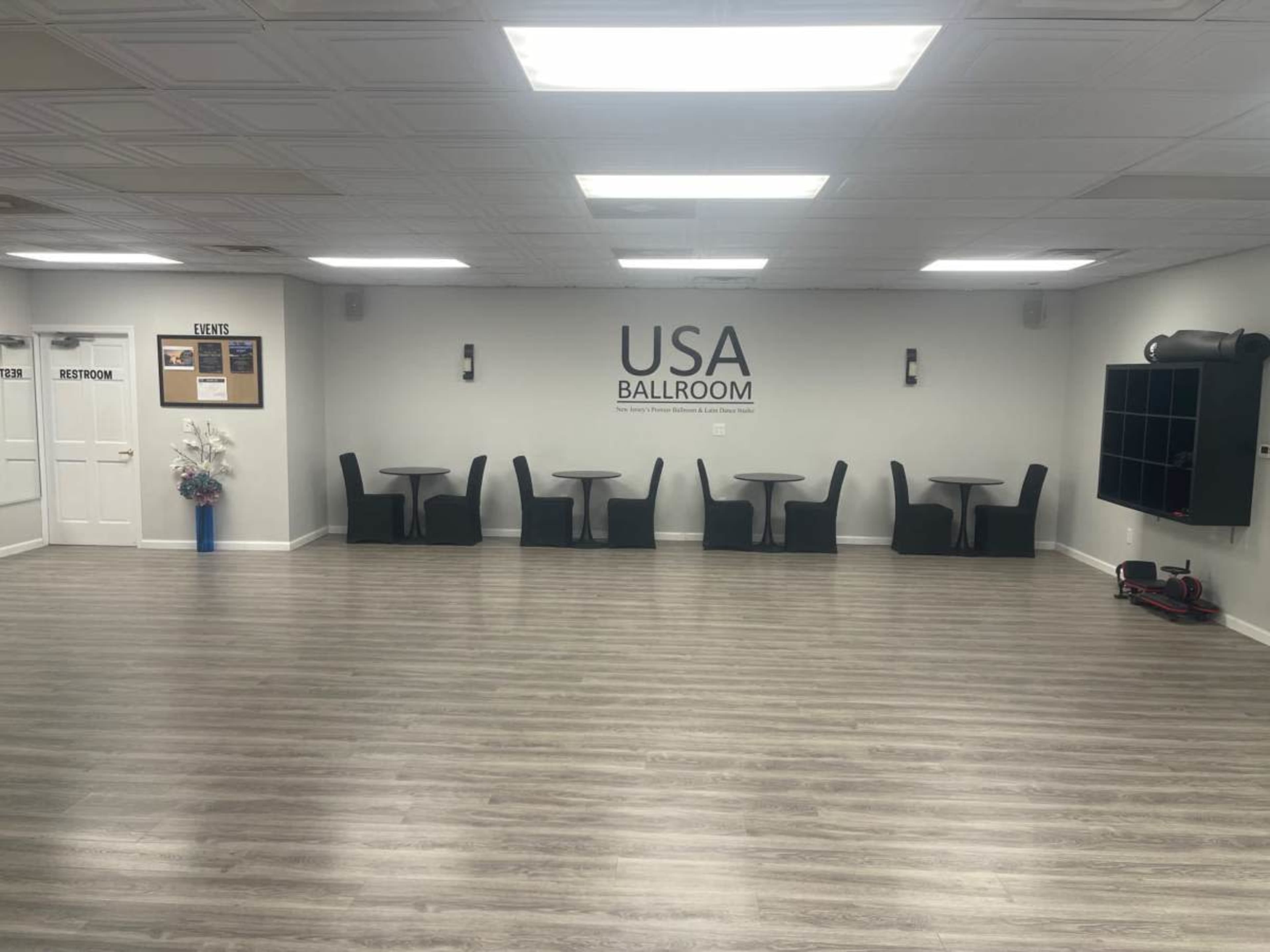 The image shows a spacious ballroom with several tables and chairs arranged against the walls, alongside a large sign labeled "USA BALLROOM."