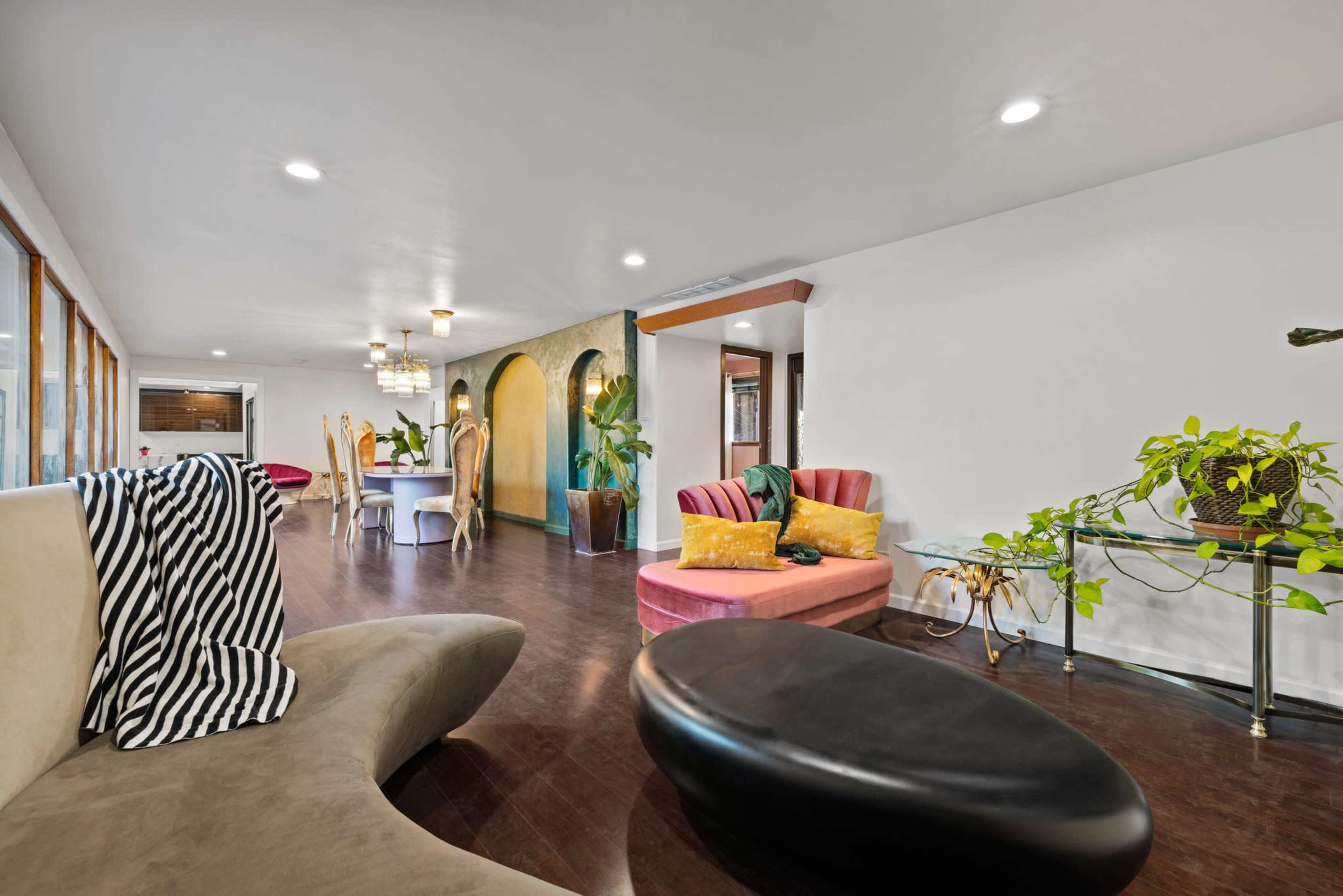 A modern, open-concept living area featuring a mix of seating options and dining spaces, with large windows allowing natural light to fill the room.