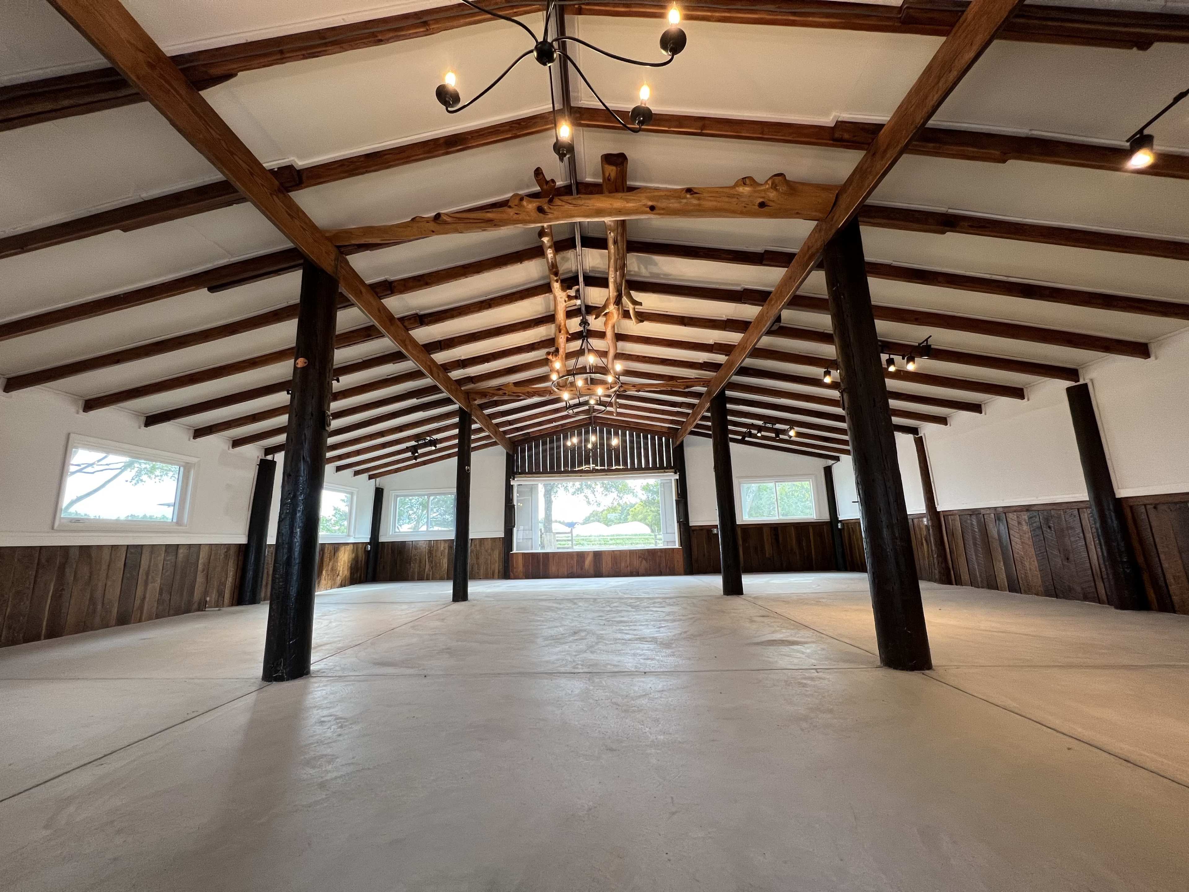 A spacious interior with exposed wooden beams, a polished concrete floor, and multiple windows allowing natural light in.