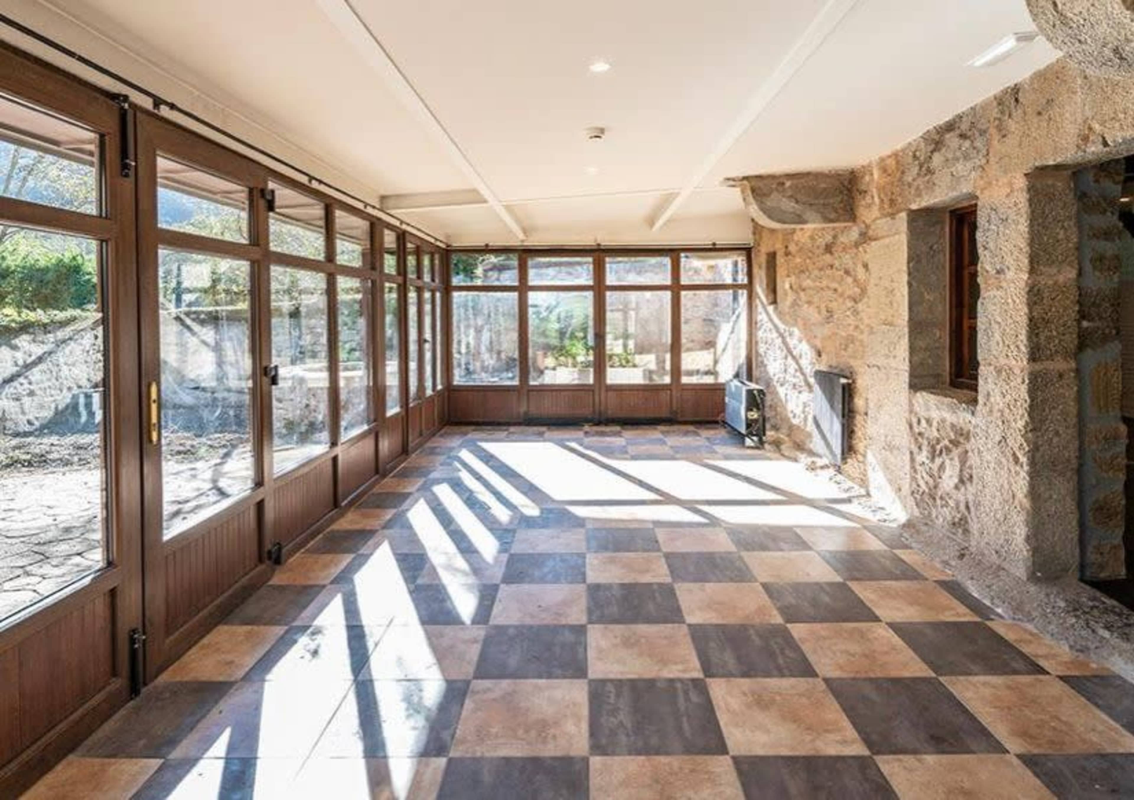The image shows a spacious sunroom with large windows and a checkerboard tile floor.