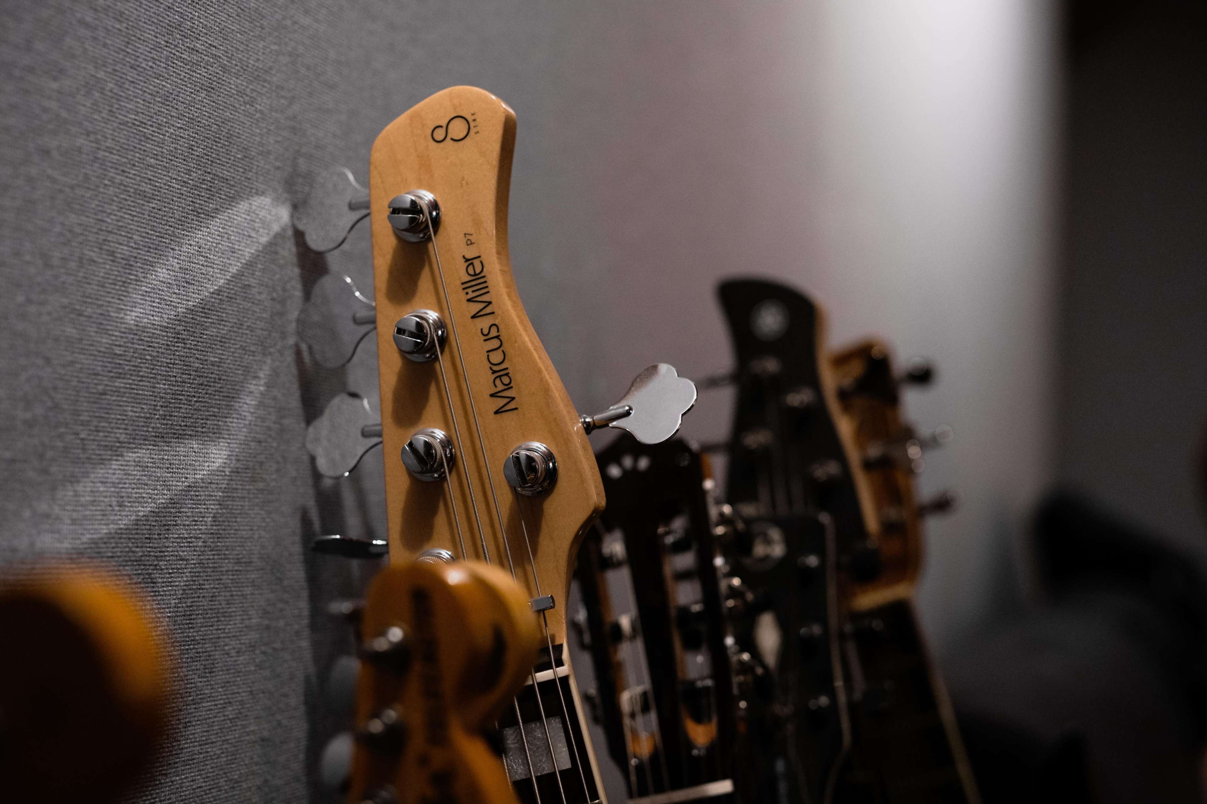 A row of various guitar heads is displayed against a gray wall.