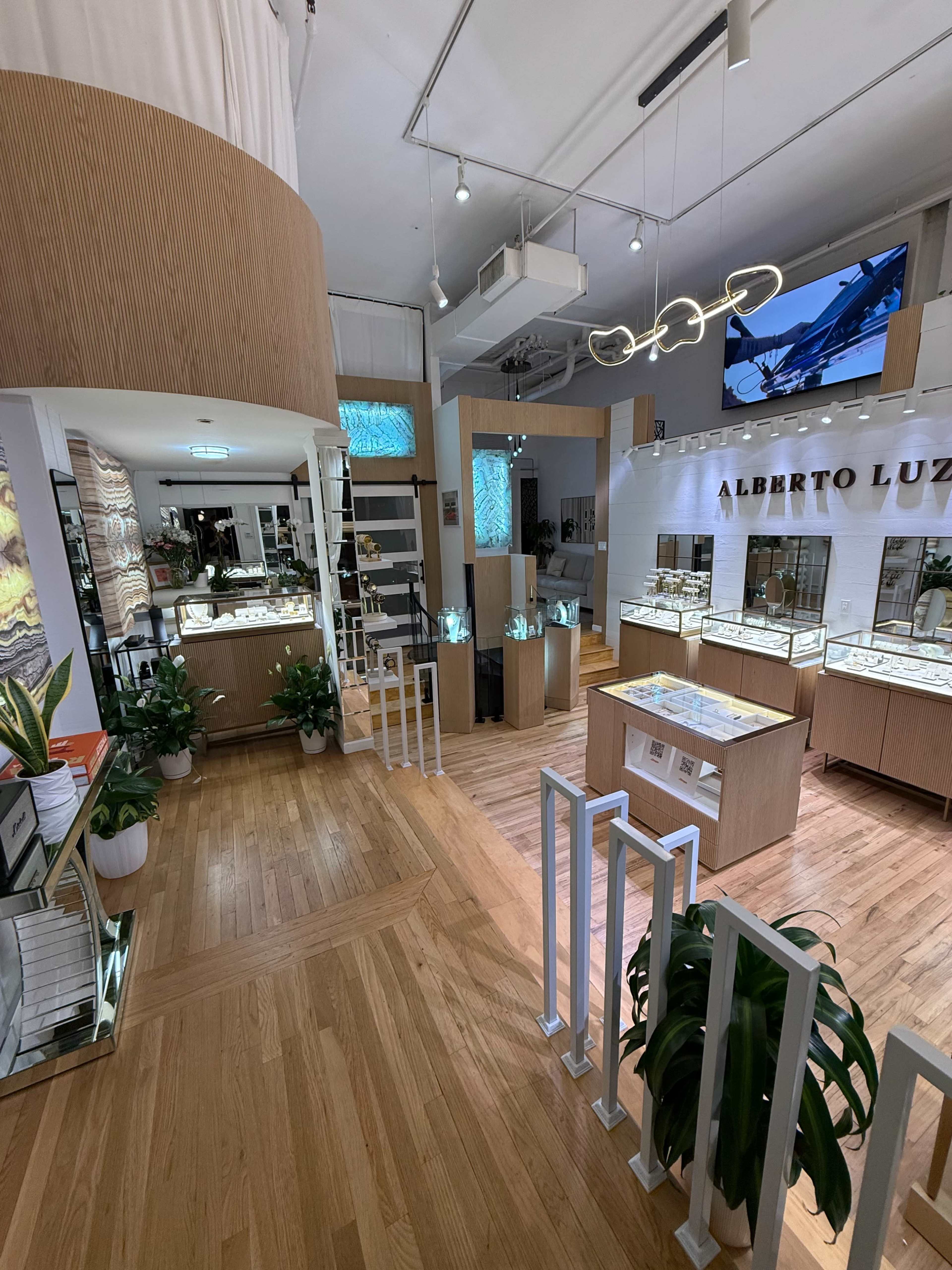 The image shows a jewelry store interior featuring wooden displays, modern lighting, and various showcases filled with jewelry.