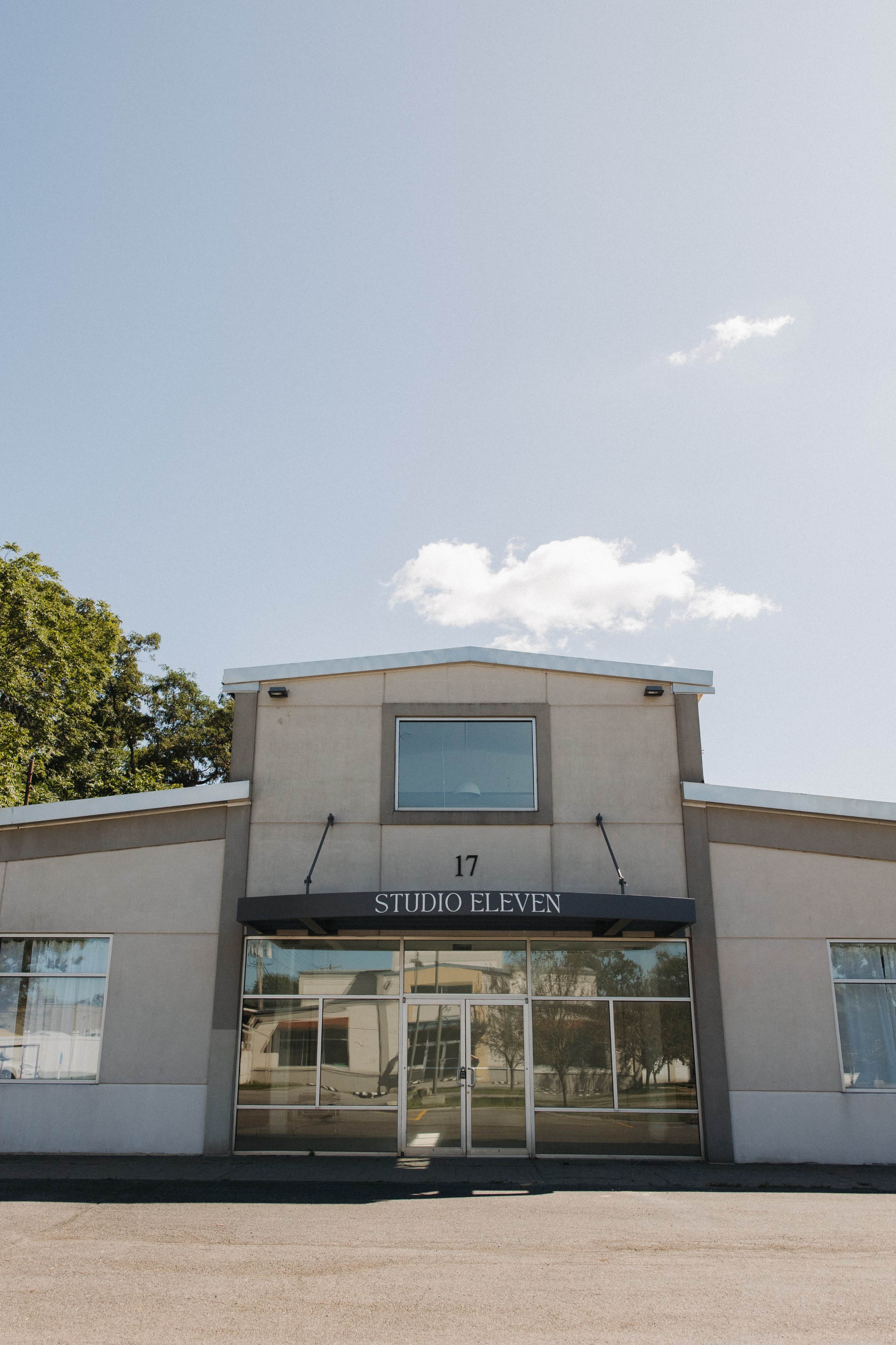 The image shows a single-story building labeled "STUDIO ELEVEN" with large glass windows and a clear blue sky above.