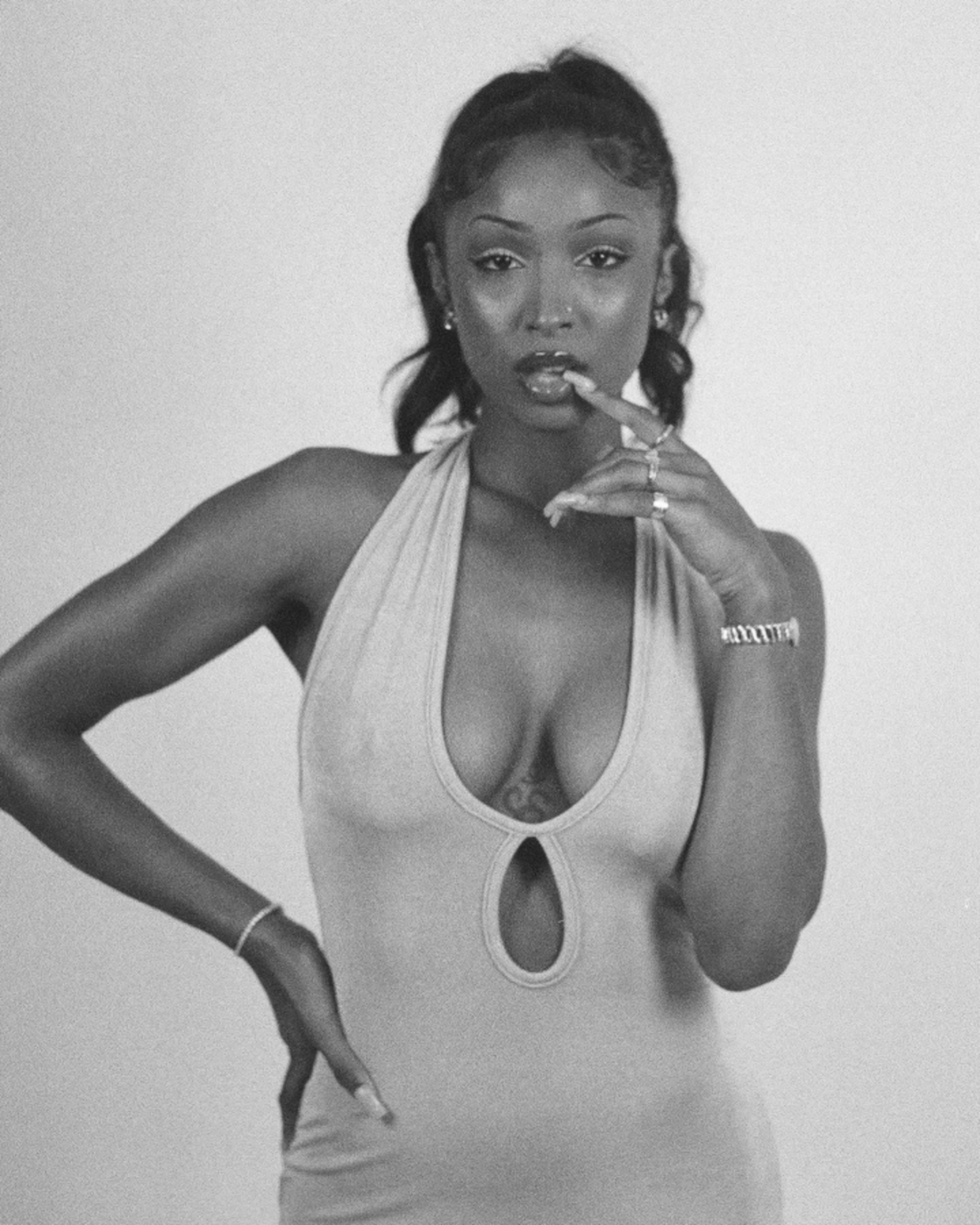 A woman poses confidently while wearing a sleeveless, form-fitting dress with a keyhole cutout.