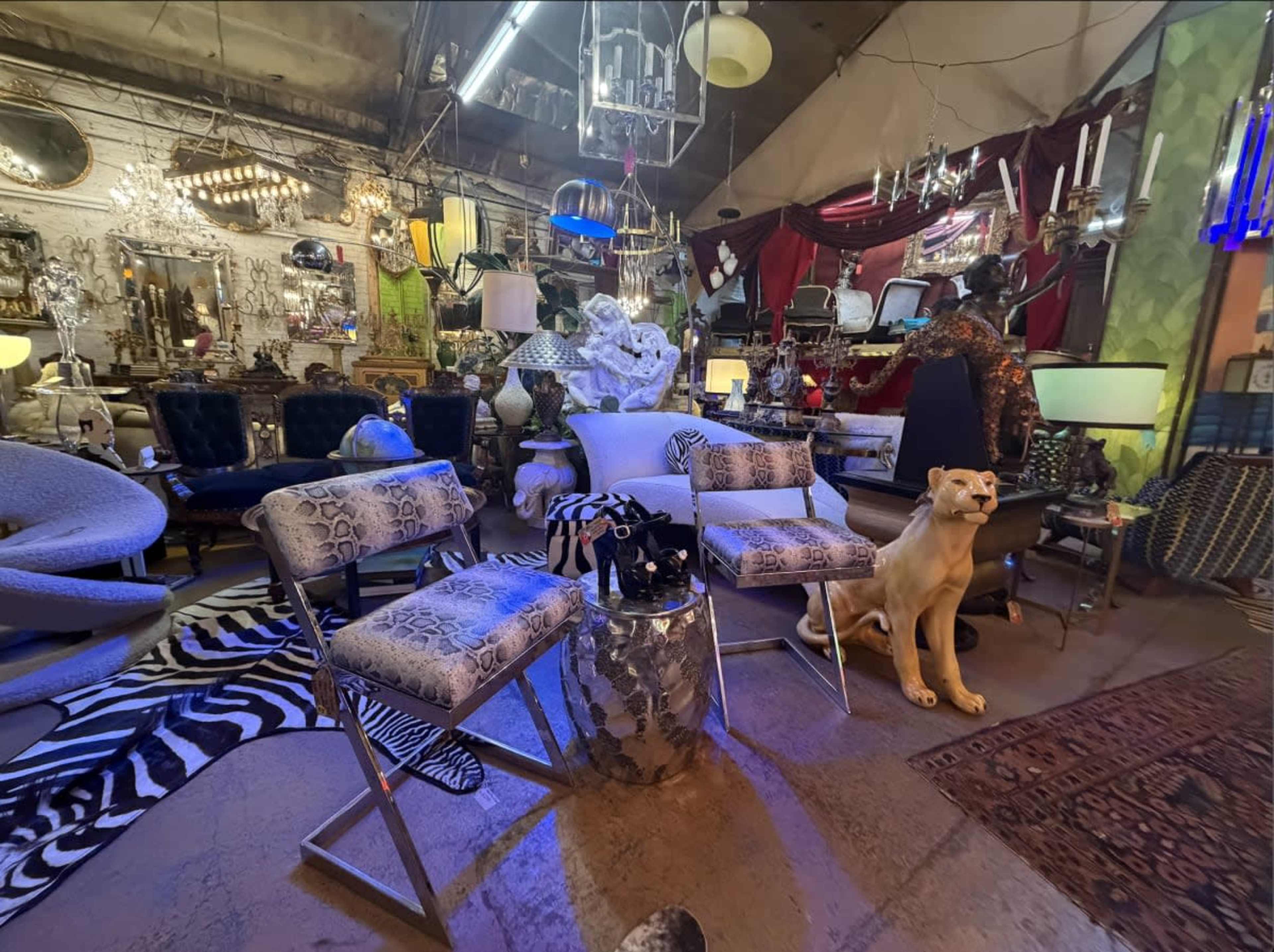 The image shows a vintage store filled with eclectic furniture, decor items, and animal-themed sculptures.