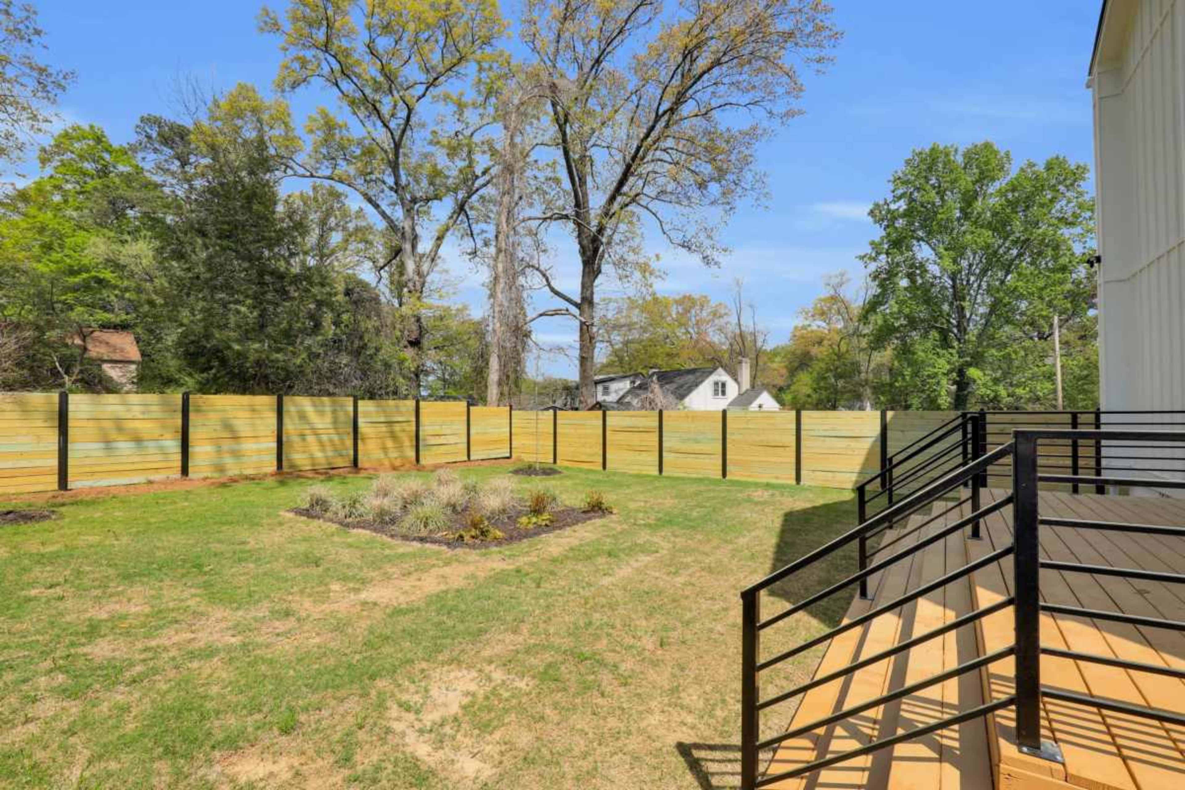 The image shows a backyard with a wooden fence, grass, and a staircase leading to a patio.