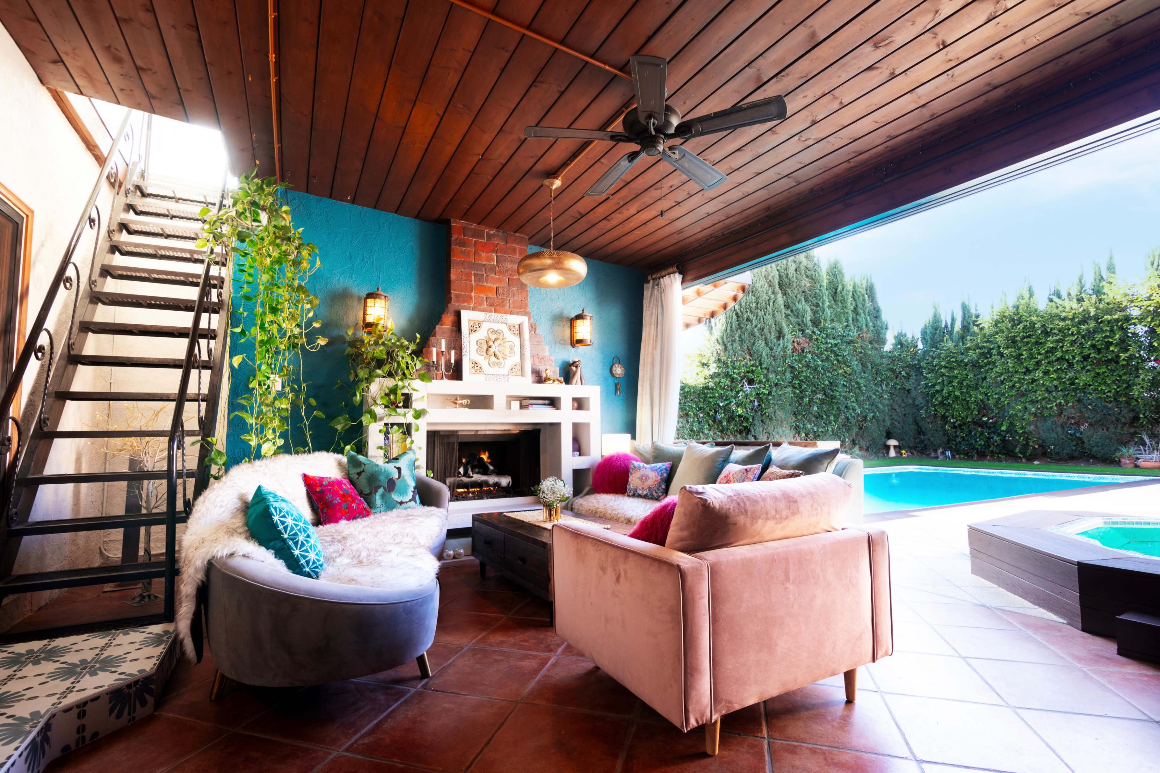 A cozy living room with a fireplace and modern seating, leading to a pool area visible through large sliding glass doors.