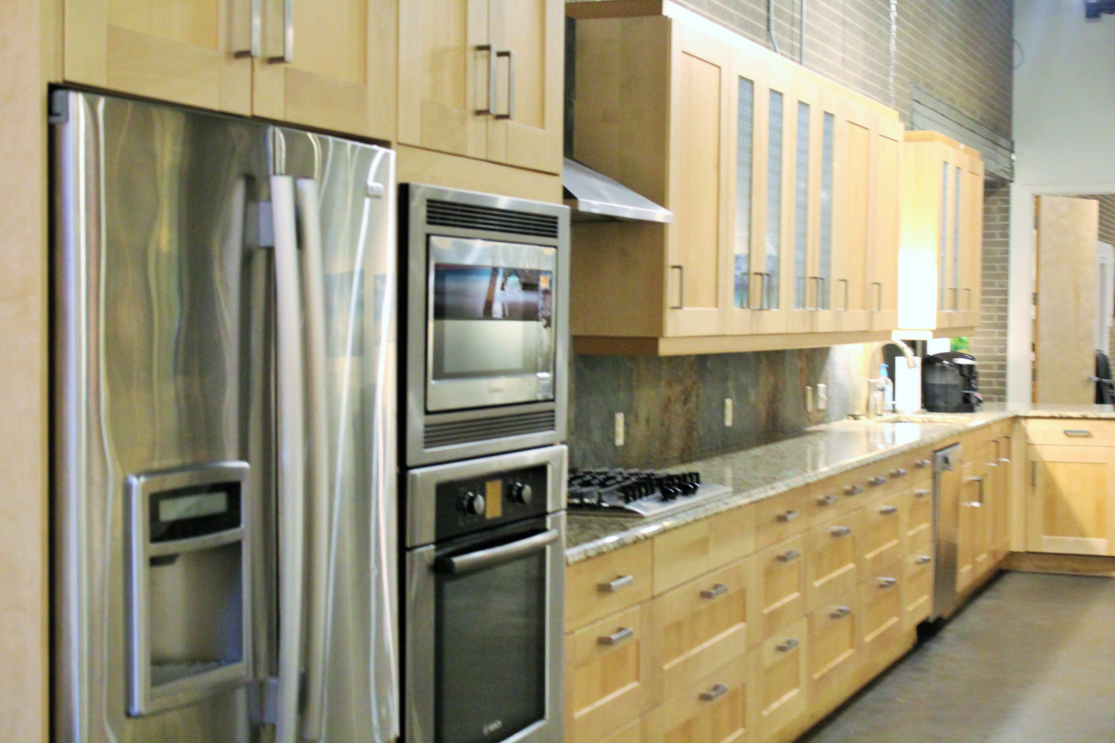 The image shows a modern kitchen with stainless steel appliances, wooden cabinetry, and a granite countertop.