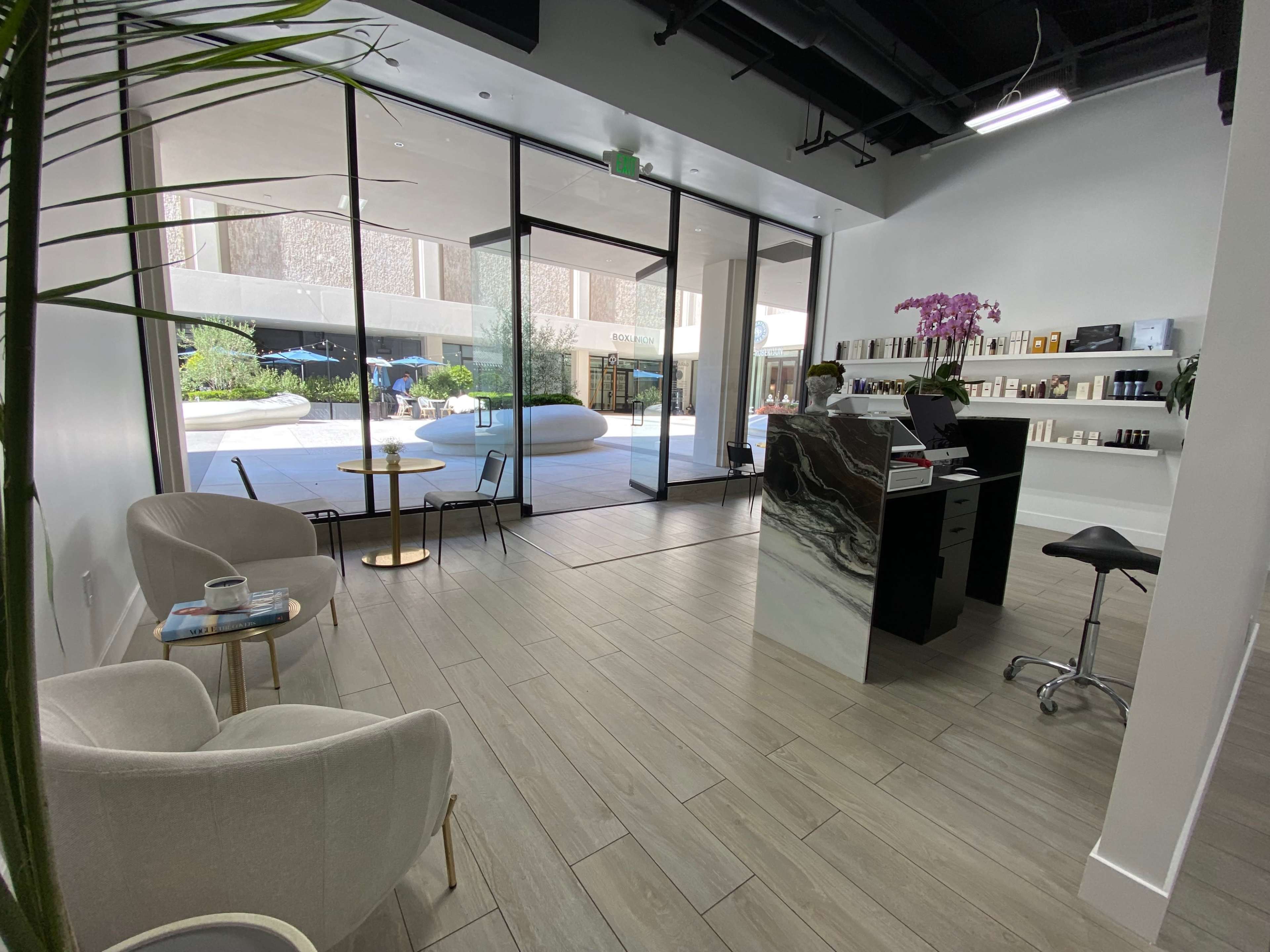 A bright, modern reception area with a sleek front desk and seating near large windows that overlook an outdoor space.