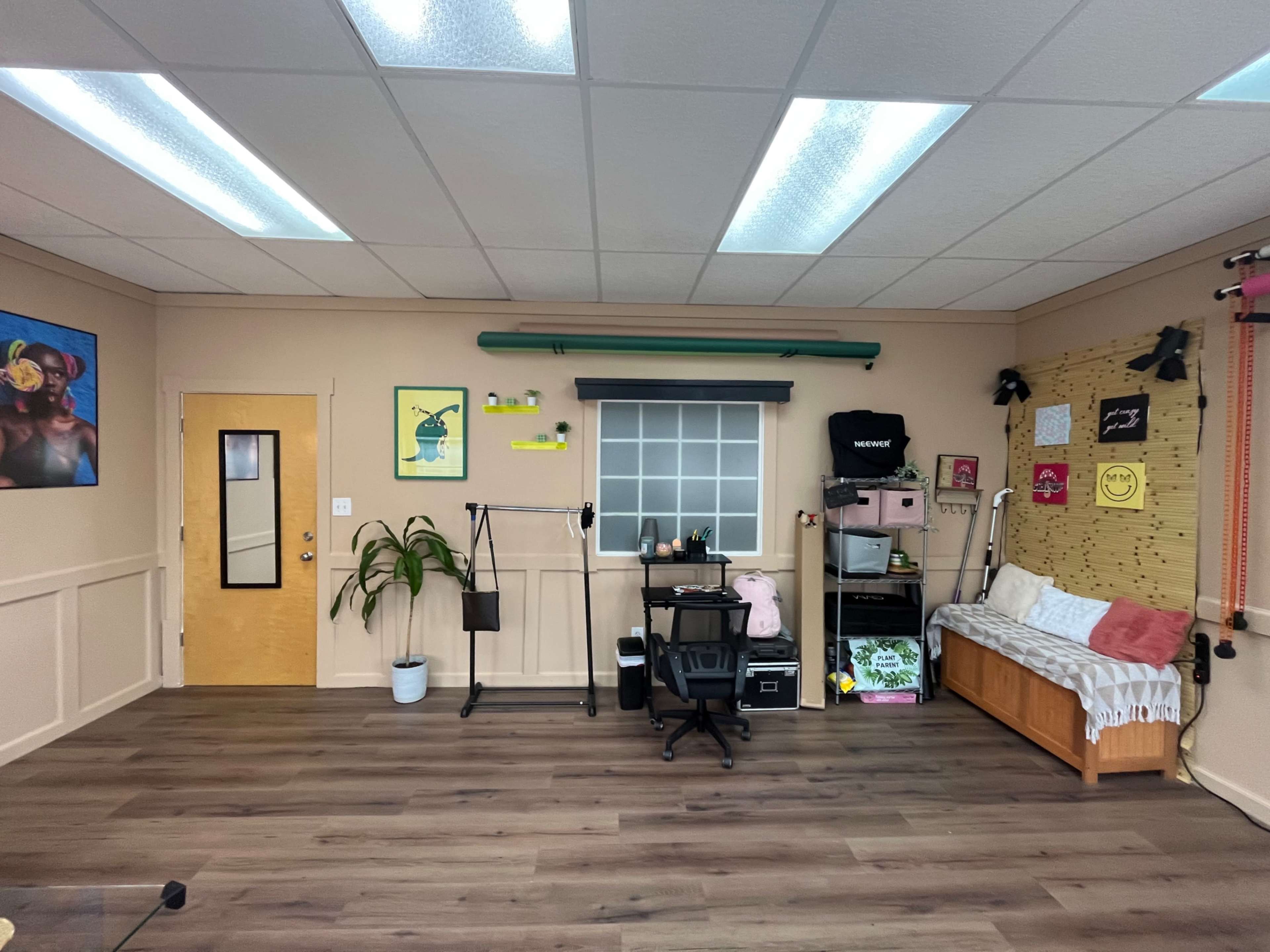 A well-organized room featuring a bed, a desk with a chair, a door, and various decorations on the walls.
