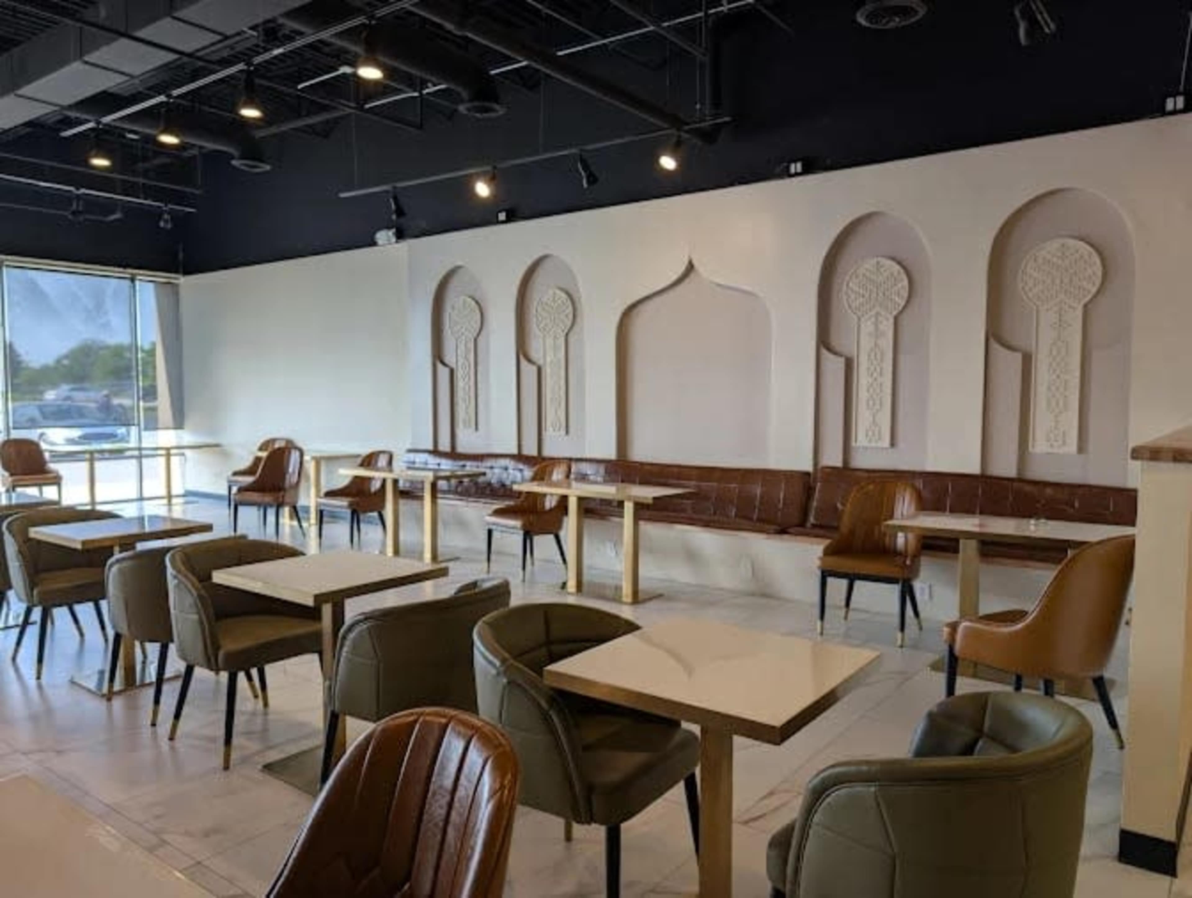 The image shows a modern cafe interior featuring leather seating and elegant architectural wall designs.