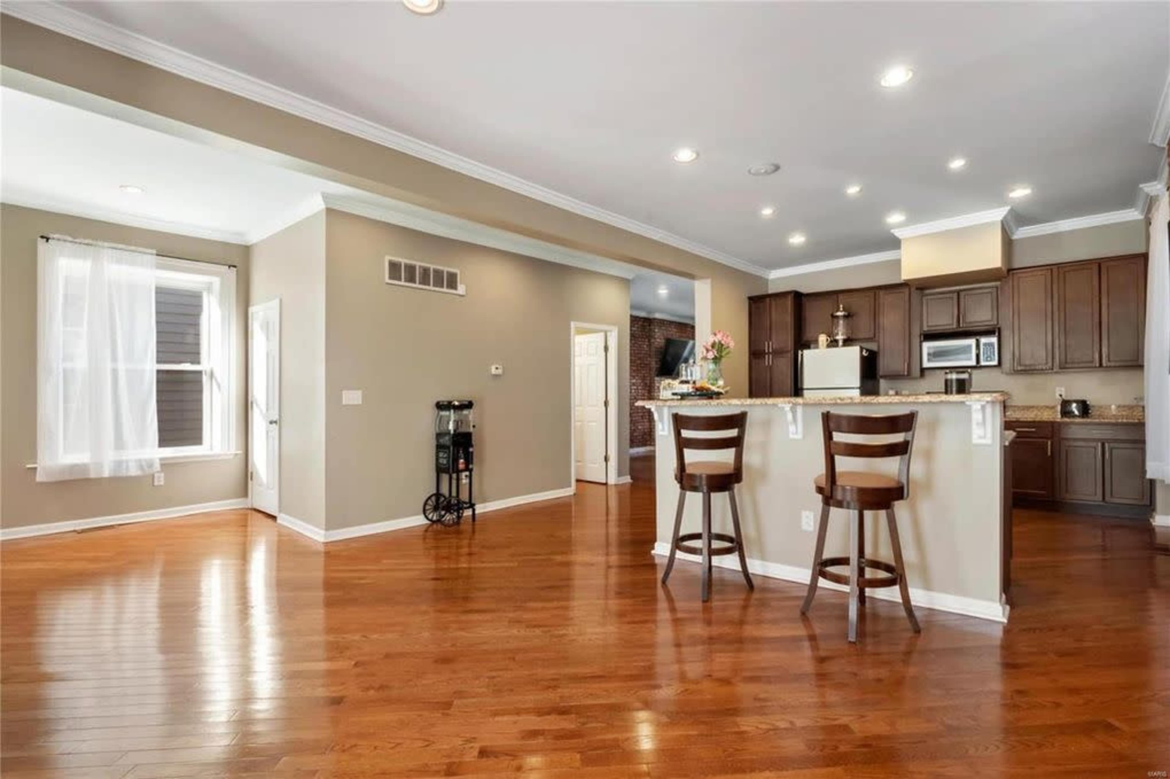 A spacious, open-concept kitchen and living area with hardwood flooring and dark wood cabinetry.