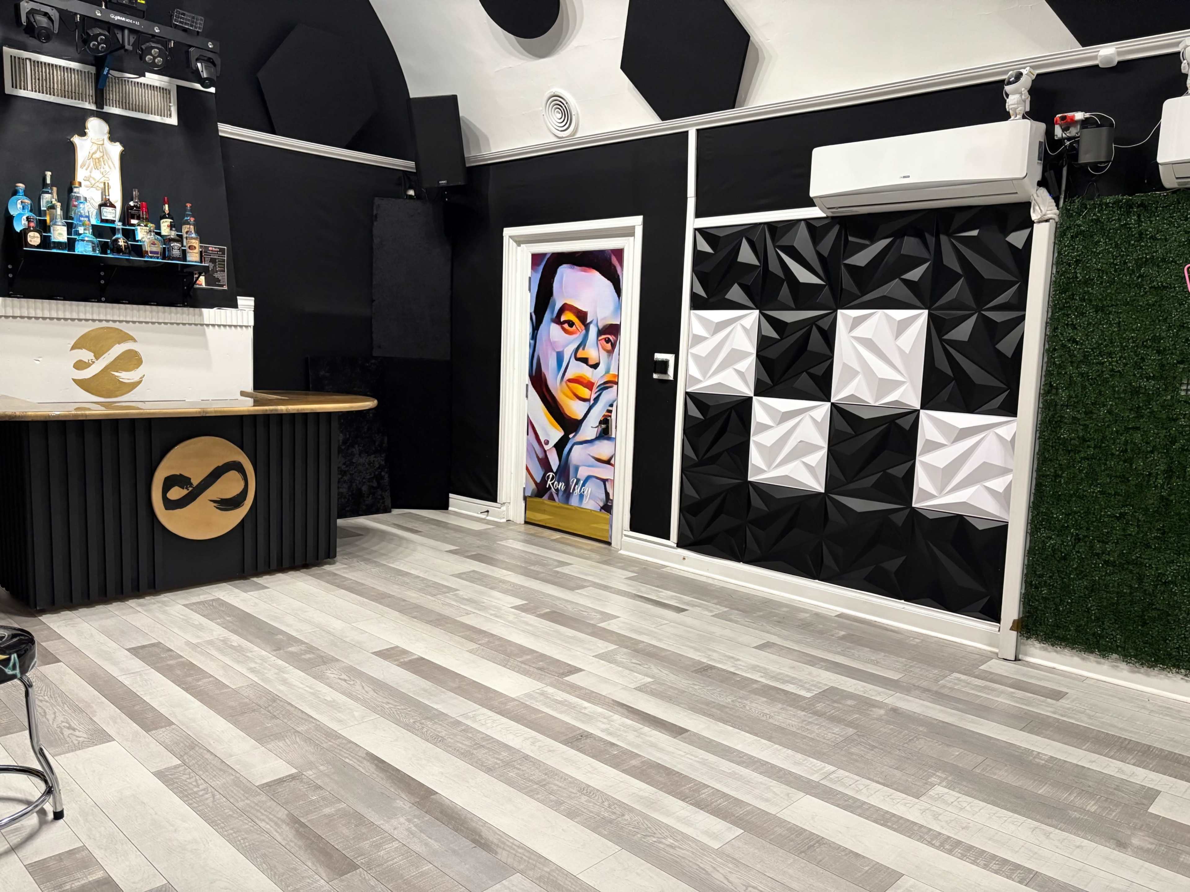 The image shows an interior space with a bar featuring a logo, a mural of a person on an adjacent door, and textured wall panels in black and white.