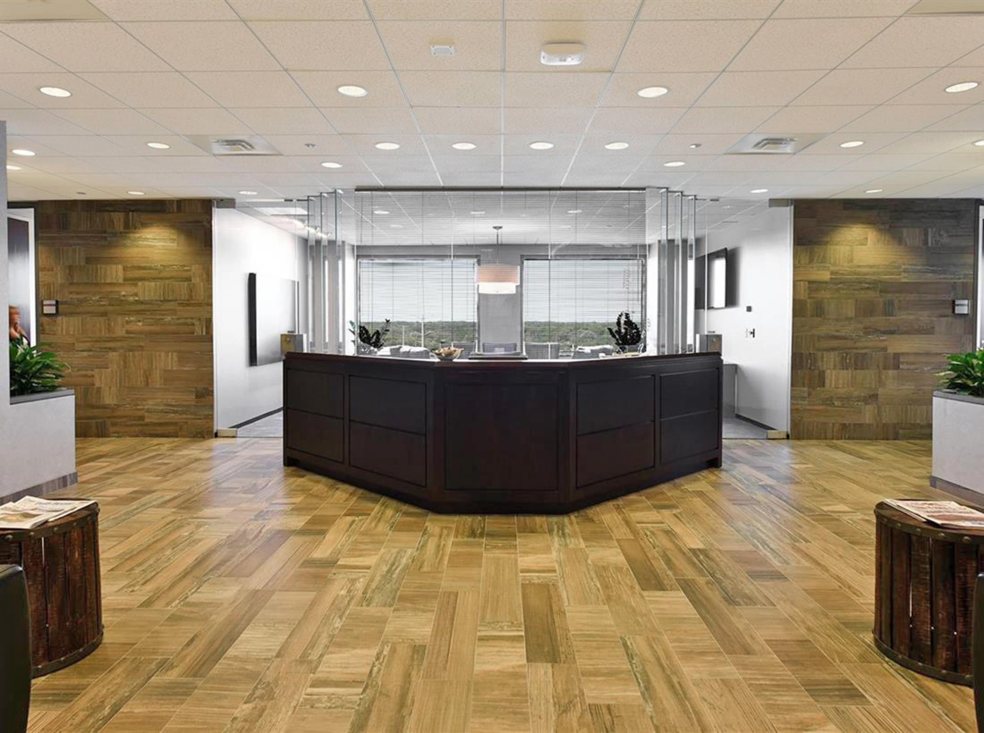 The image shows a modern reception area with a wooden front desk, large windows, and polished wooden flooring.