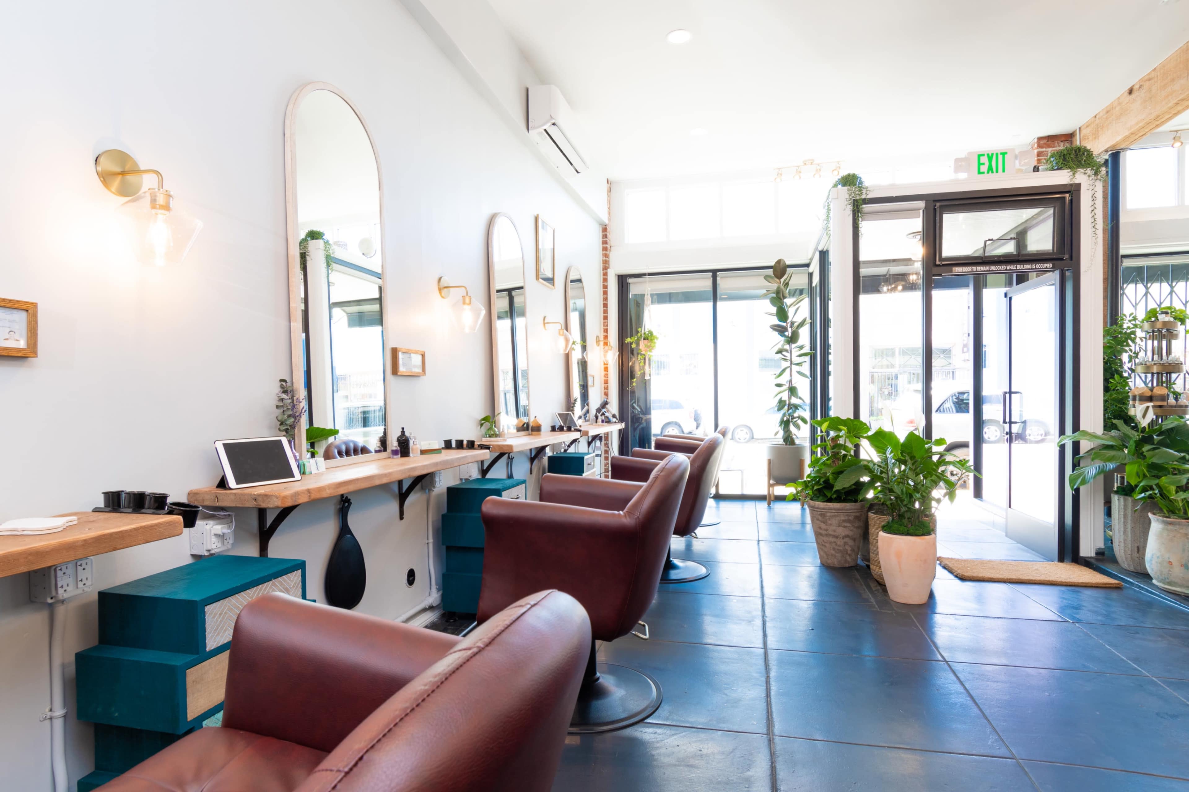 Large open gallery like salon space with brick and wood beams, high ceilings and many plants. Image in Central LA, Los Angeles, CA