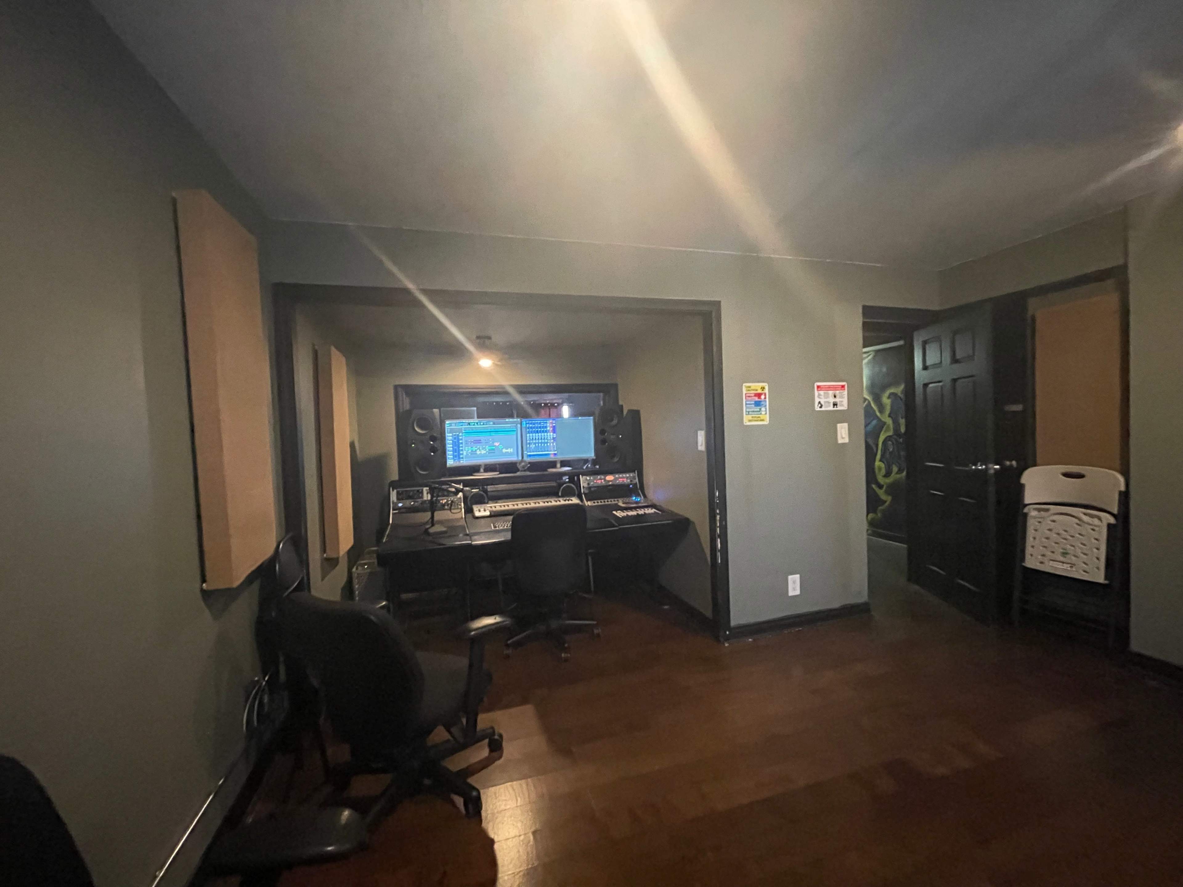 A sound recording studio with a computer workstation, audio equipment, and two empty chairs.