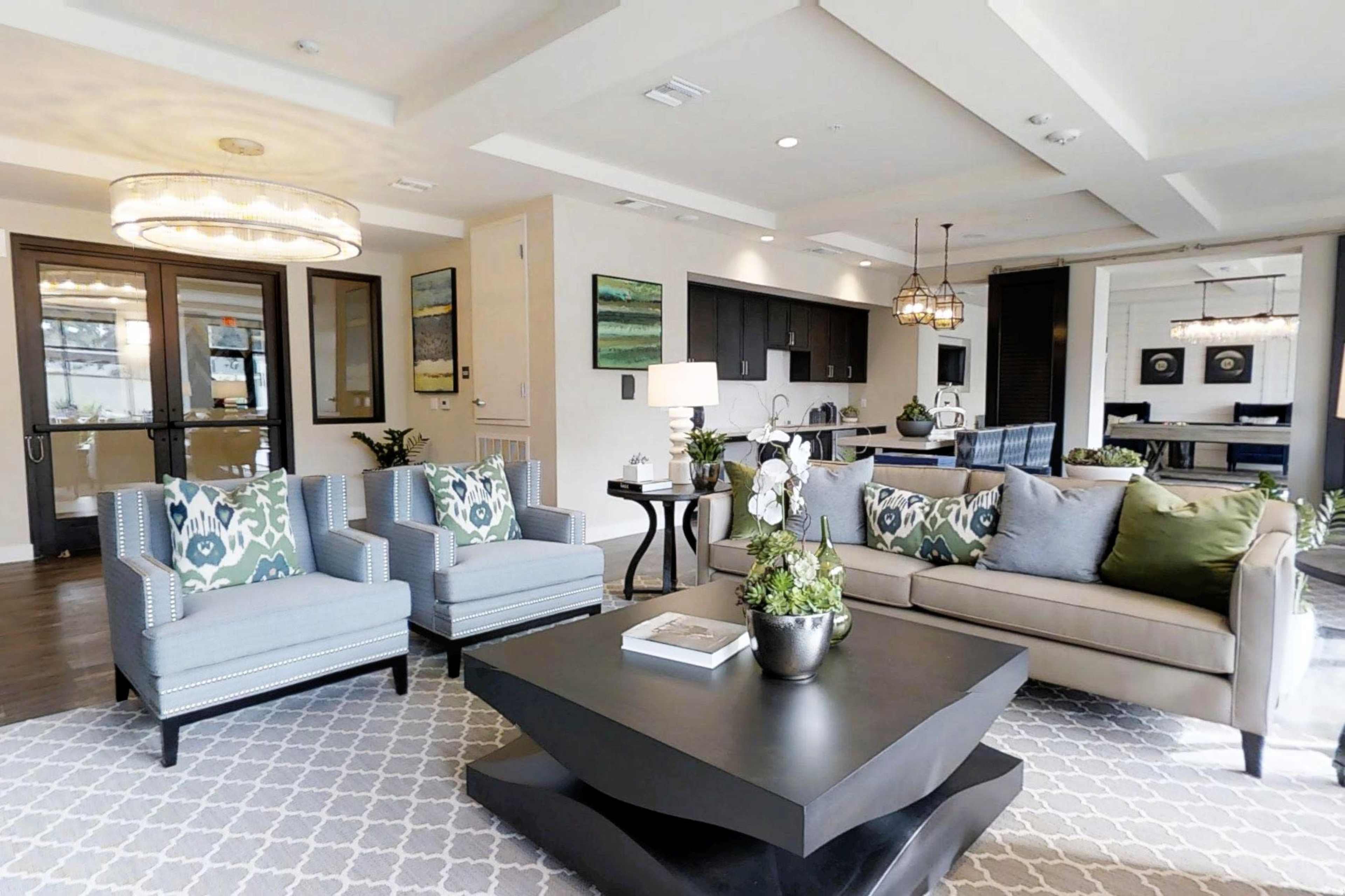 The image shows a modern living room with two patterned armchairs, a sofa, a coffee table, and an open kitchen area visible in the background.