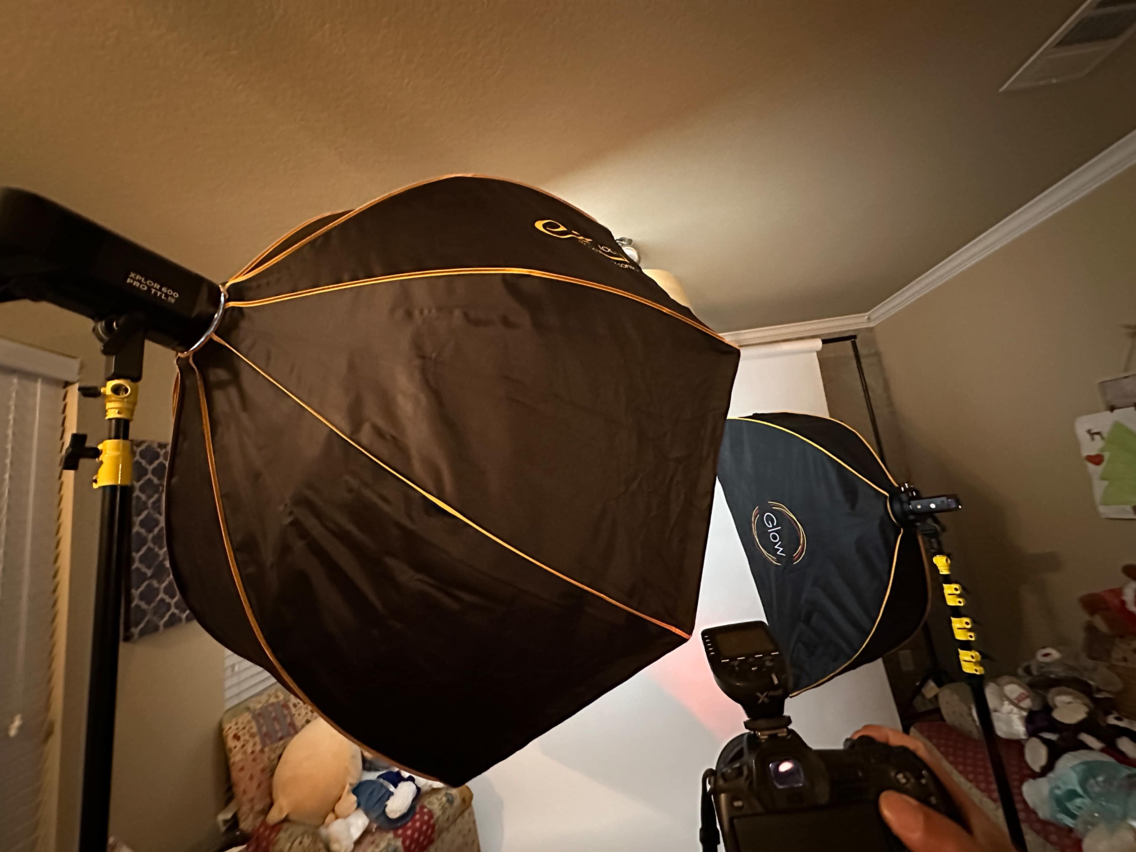 The image shows two large softbox lights set up in a room, with a camera and a backdrop partially visible in the background.
