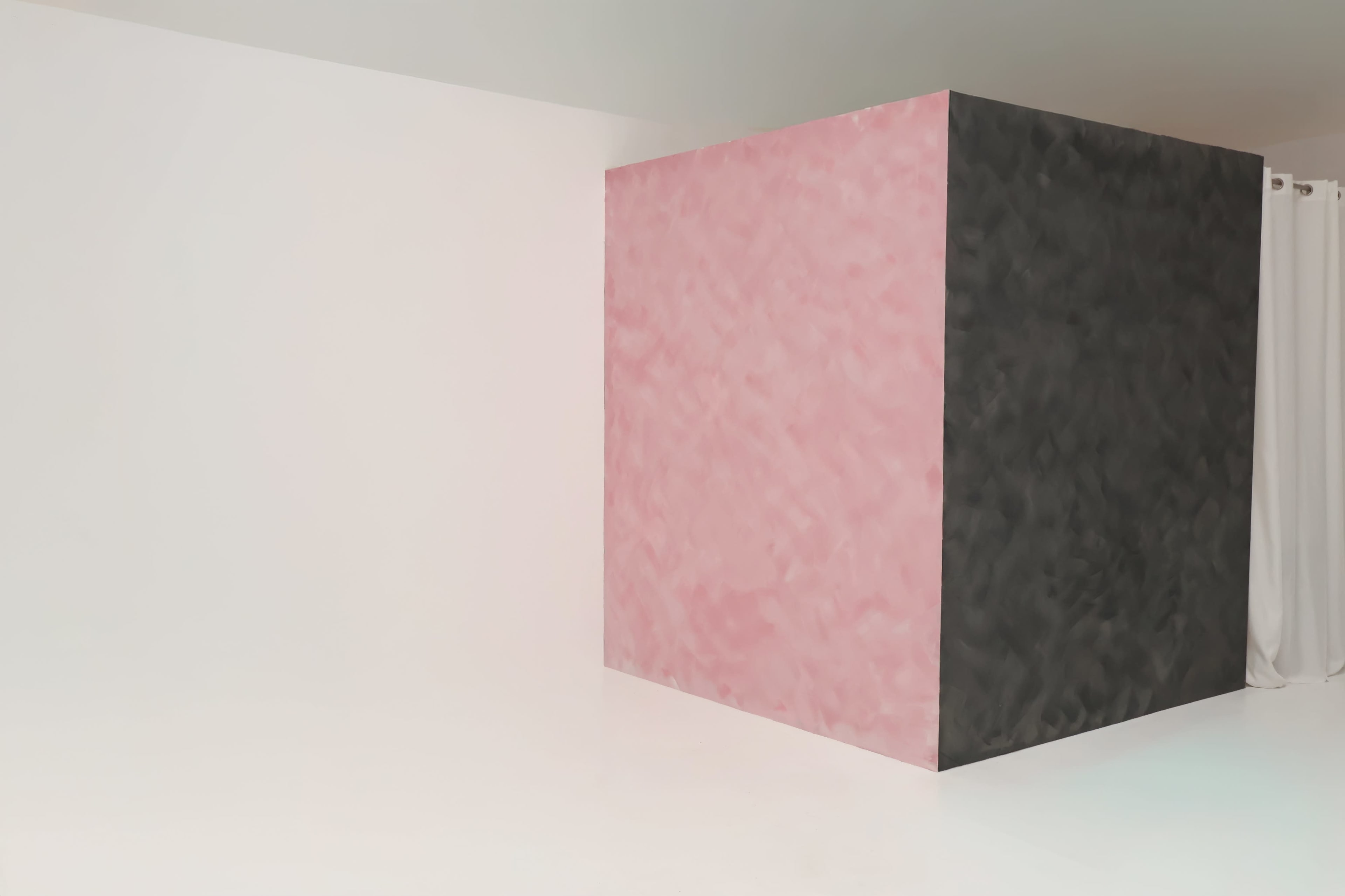 The image shows a room with a white wall on one side and a large, diamond-patterned wall painted in pink and black.