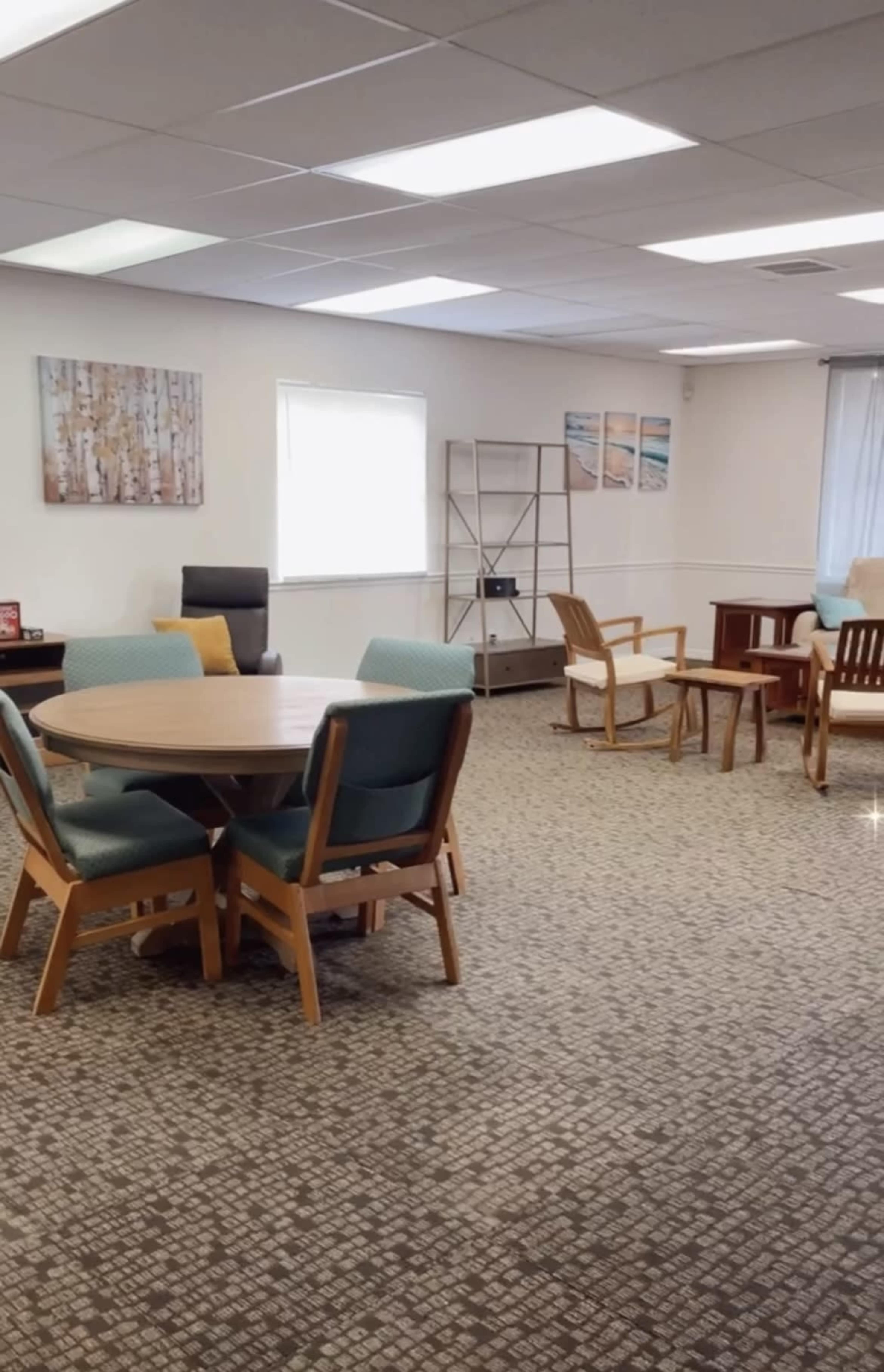 A neatly arranged interior space with a round wooden table surrounded by chairs, a seating area, and decorative wall art.