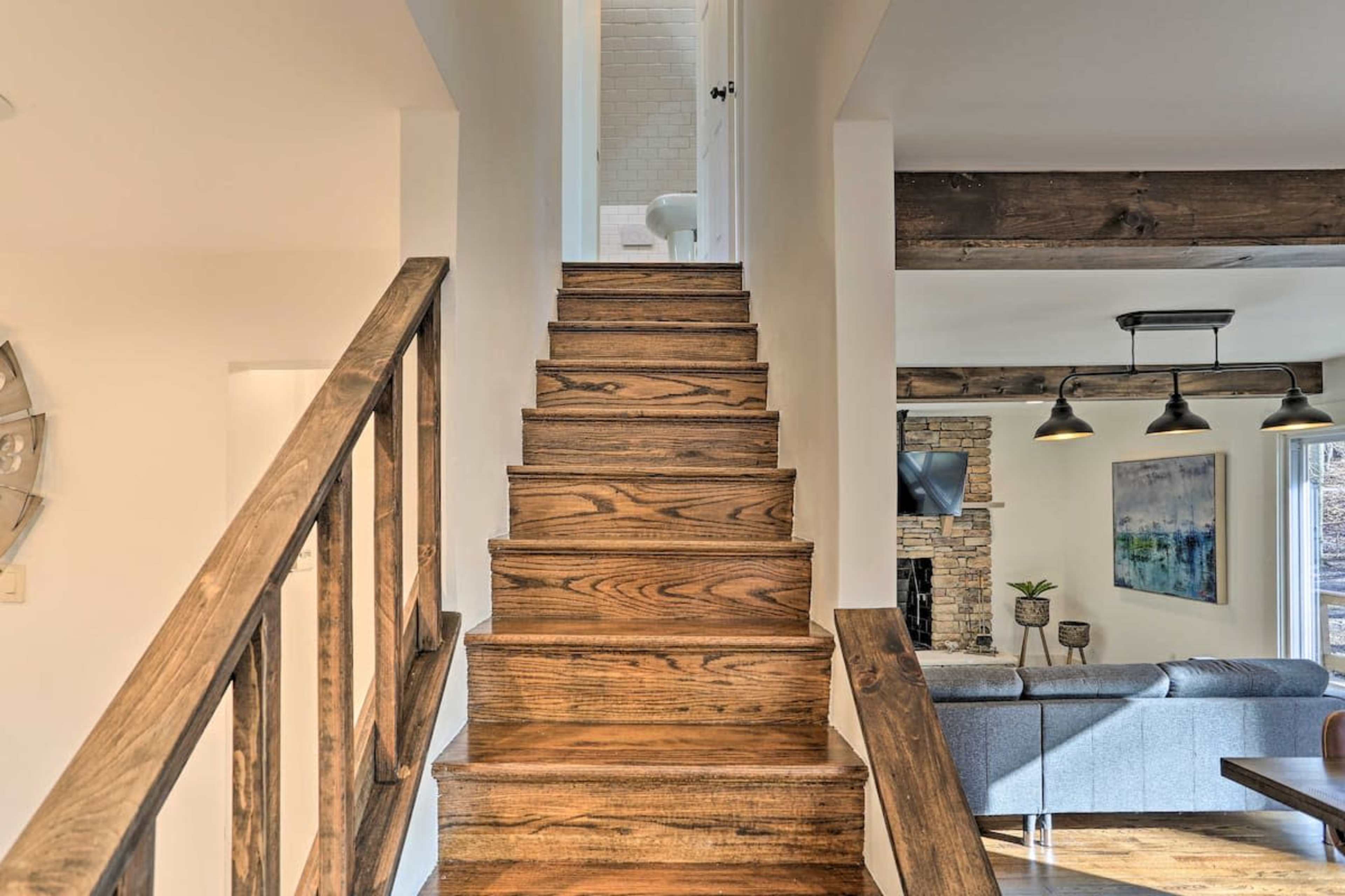 A wooden staircase leading to a white-walled hallway with a visible bathroom door at the top.