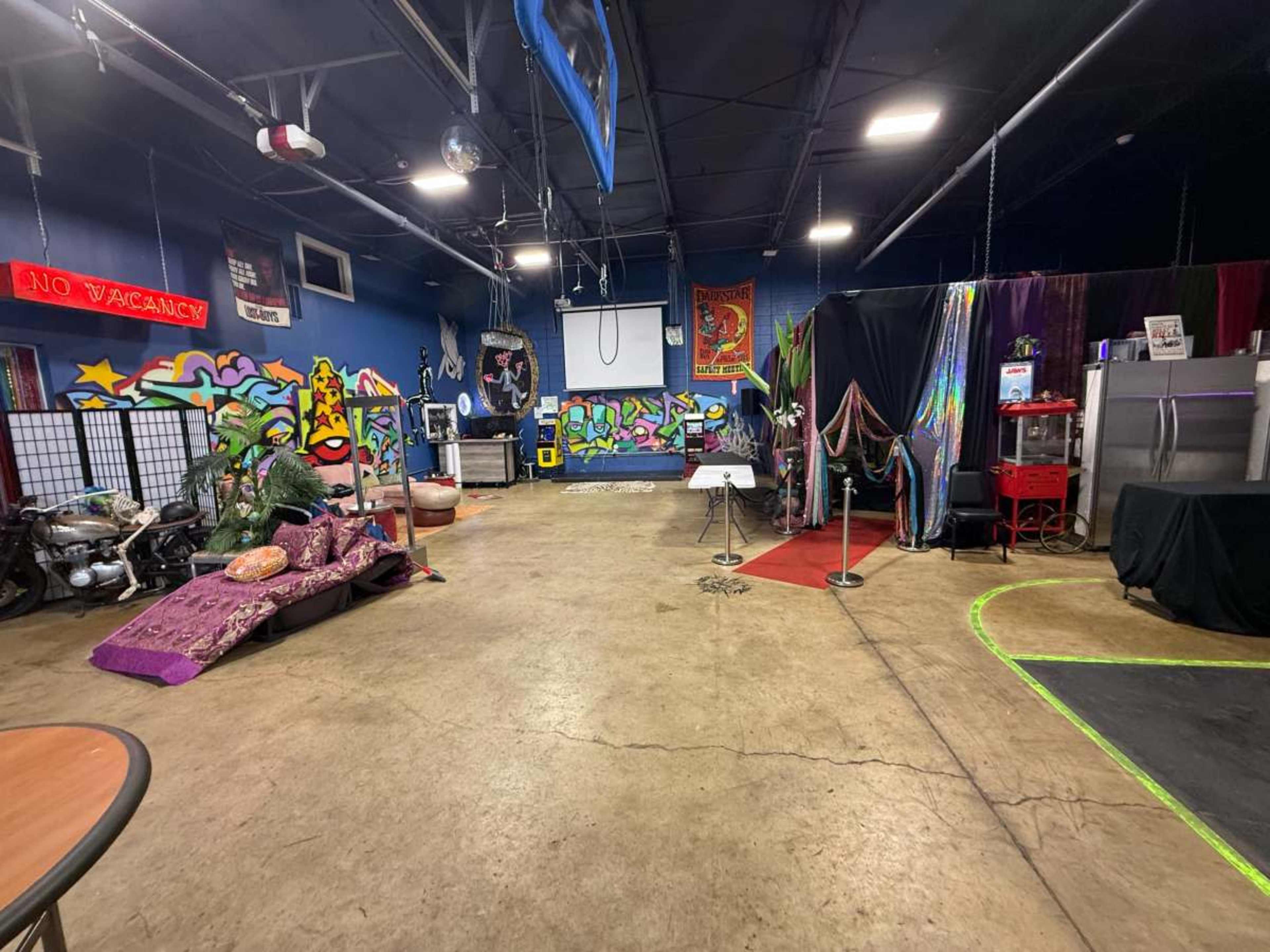 The image shows a spacious room with colorful graffiti walls, various furniture pieces, and areas designated for different activities.