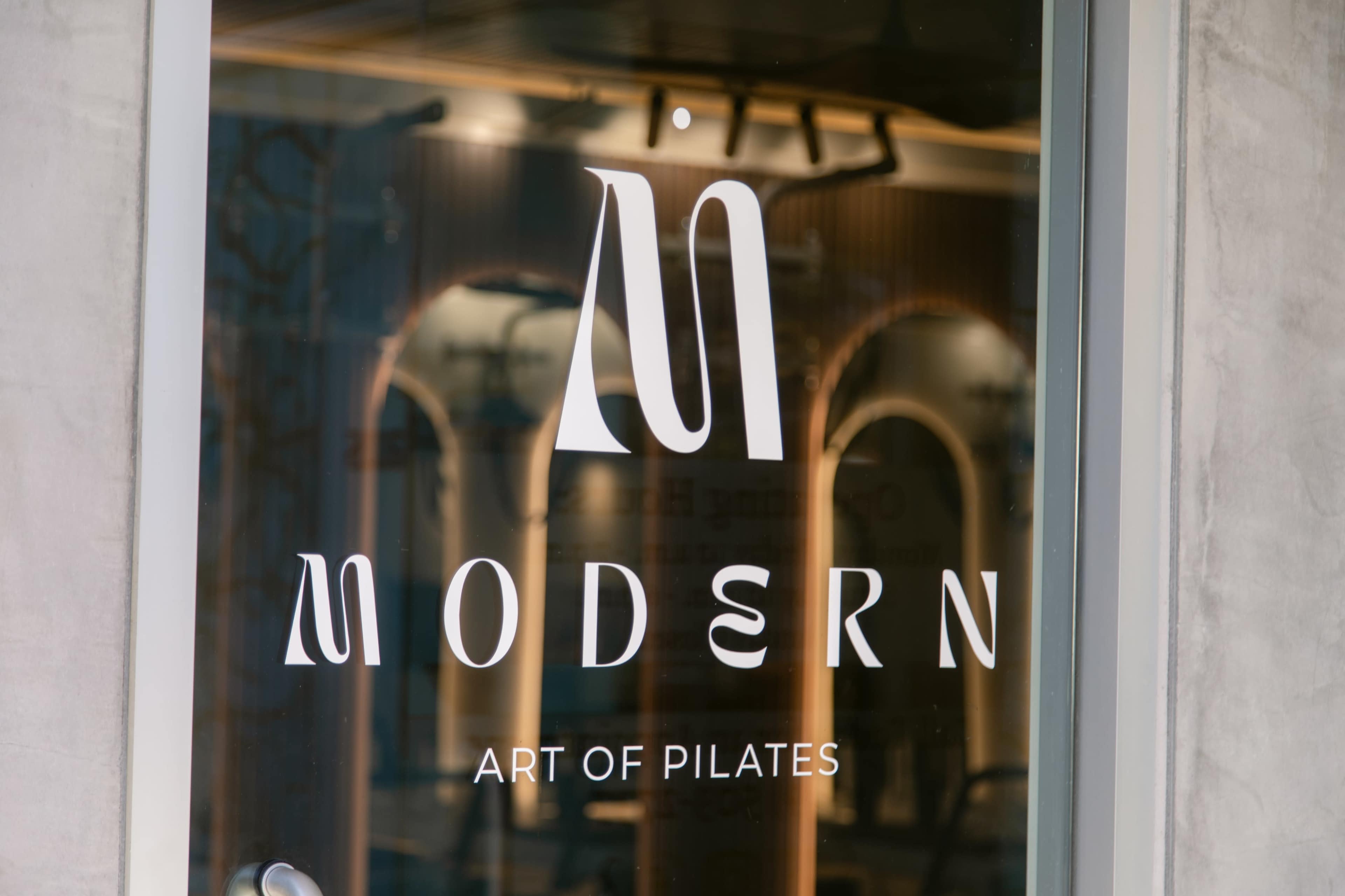The image shows a storefront window displaying the logo and name "MODERN ART OF PILATES."