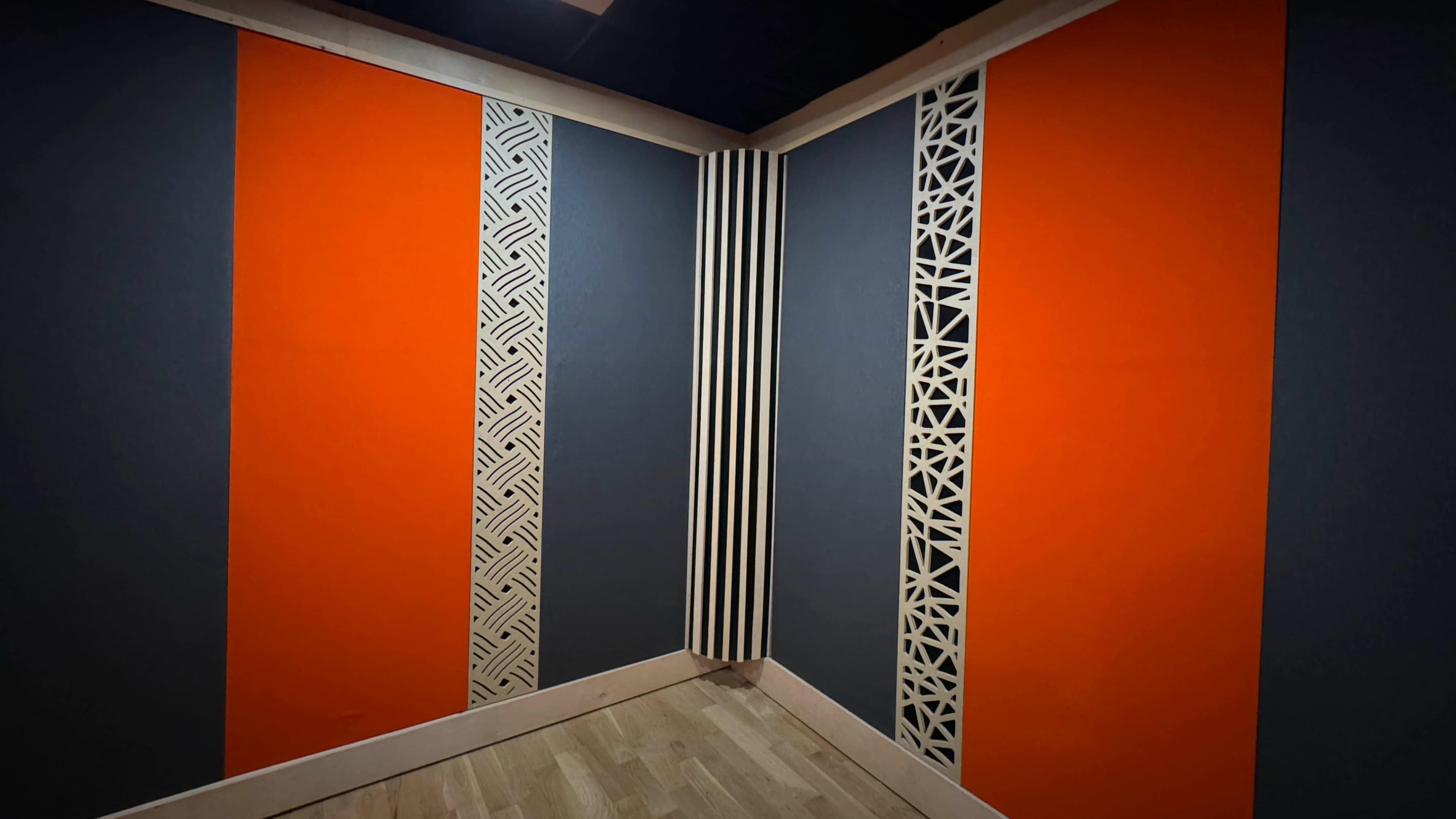 The image shows a corner of a room with orange and gray walls, featuring decorative patterns on one of the orange sections.