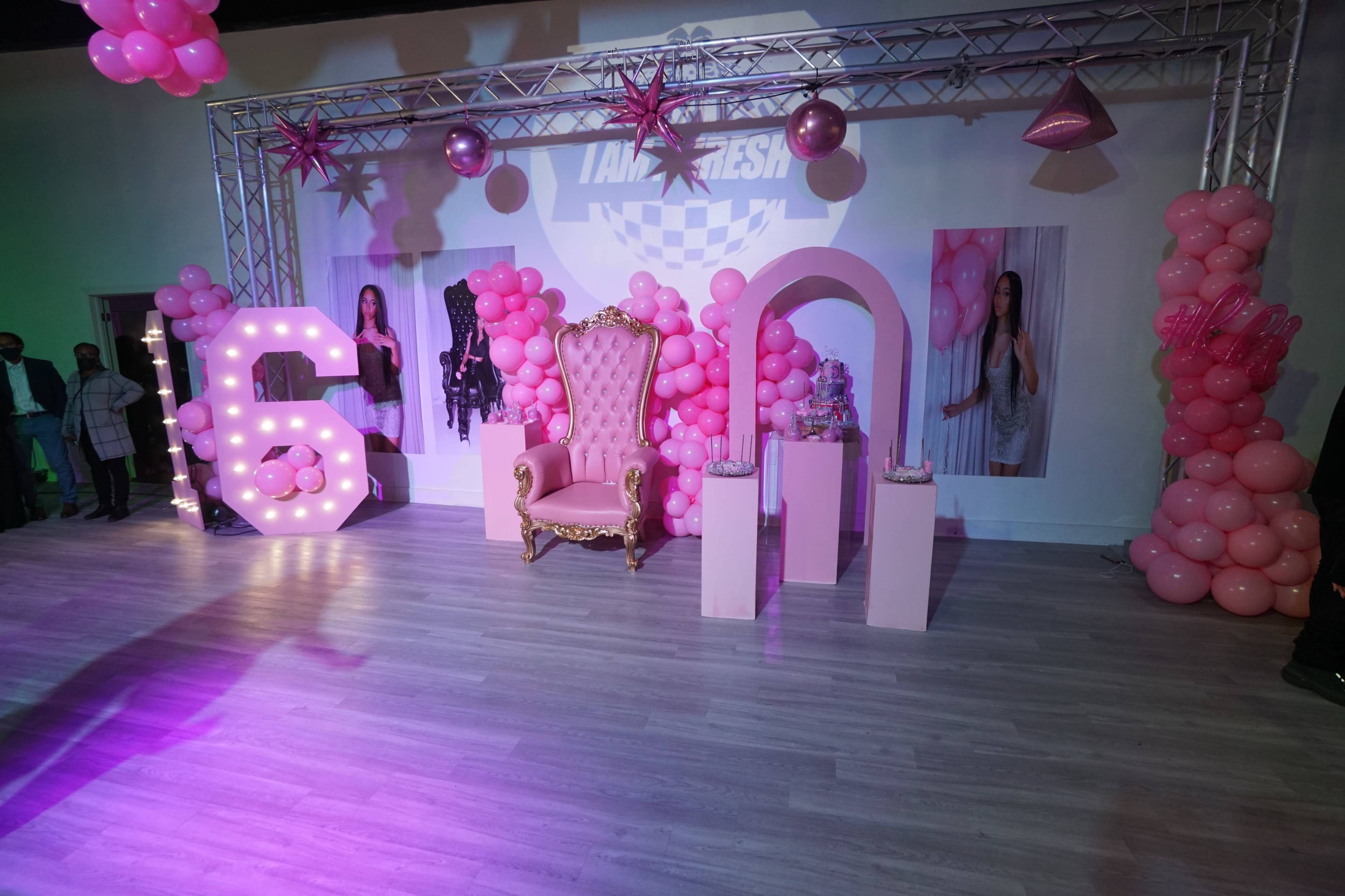 The scene features a pink-themed party setup with a large illuminated "6," a decorative throne, and balloon arrangements.