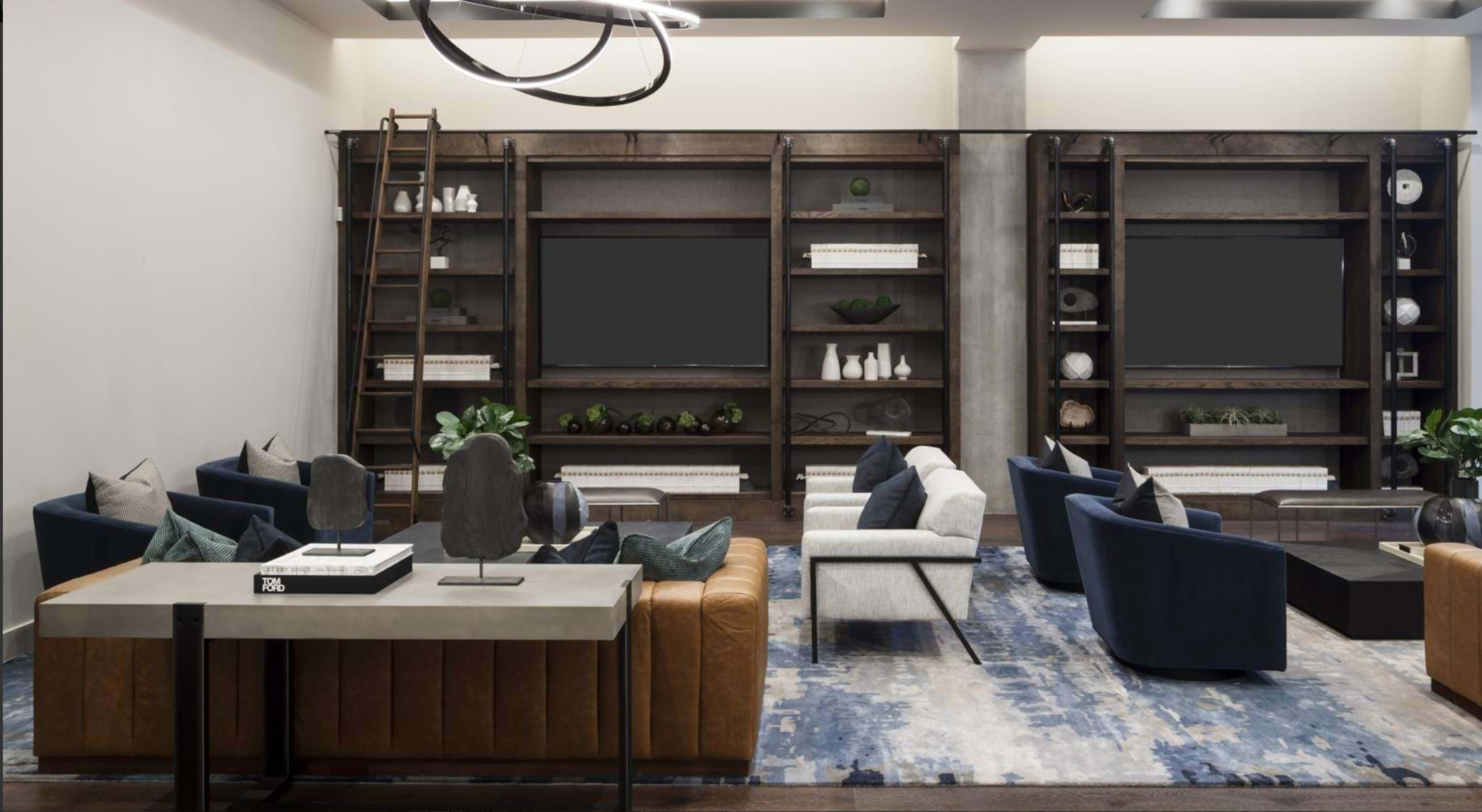The image shows a modern living space featuring a mix of leather and fabric seating, a large area rug, and built-in shelves displaying decorative items.