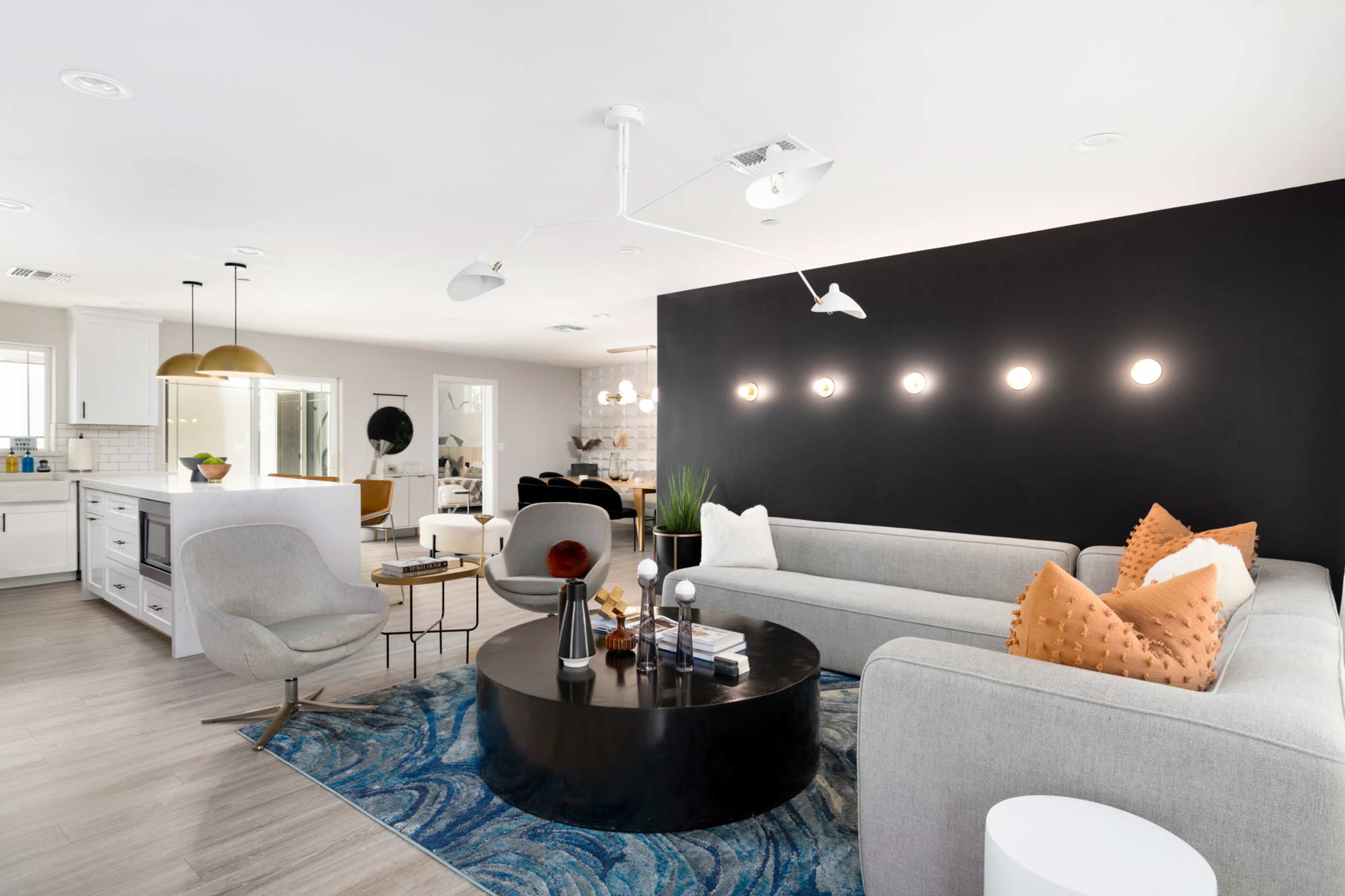 A modern living room with two gray sofas, a round black coffee table, and bright lighting against a dark accent wall.
