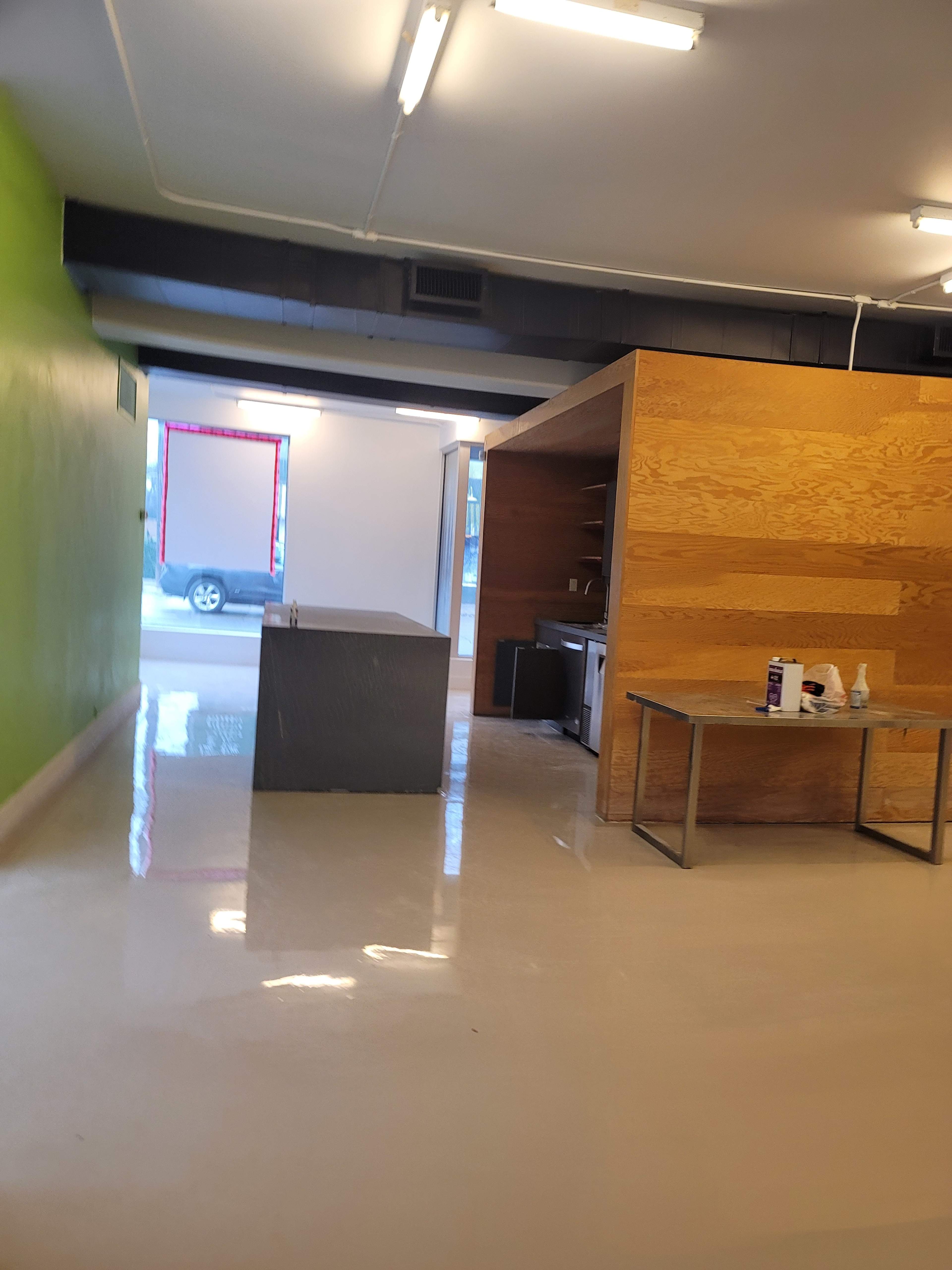 A spacious interior with a green wall, a wooden partition, and a table in an unfinished space.